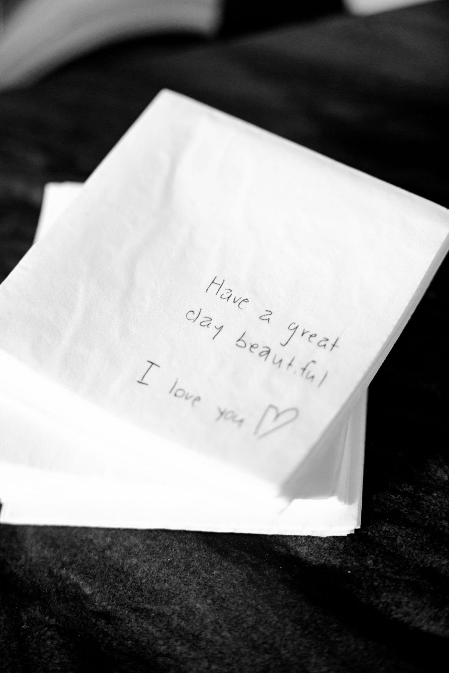 Handwritten love note on white napkin in black and white.