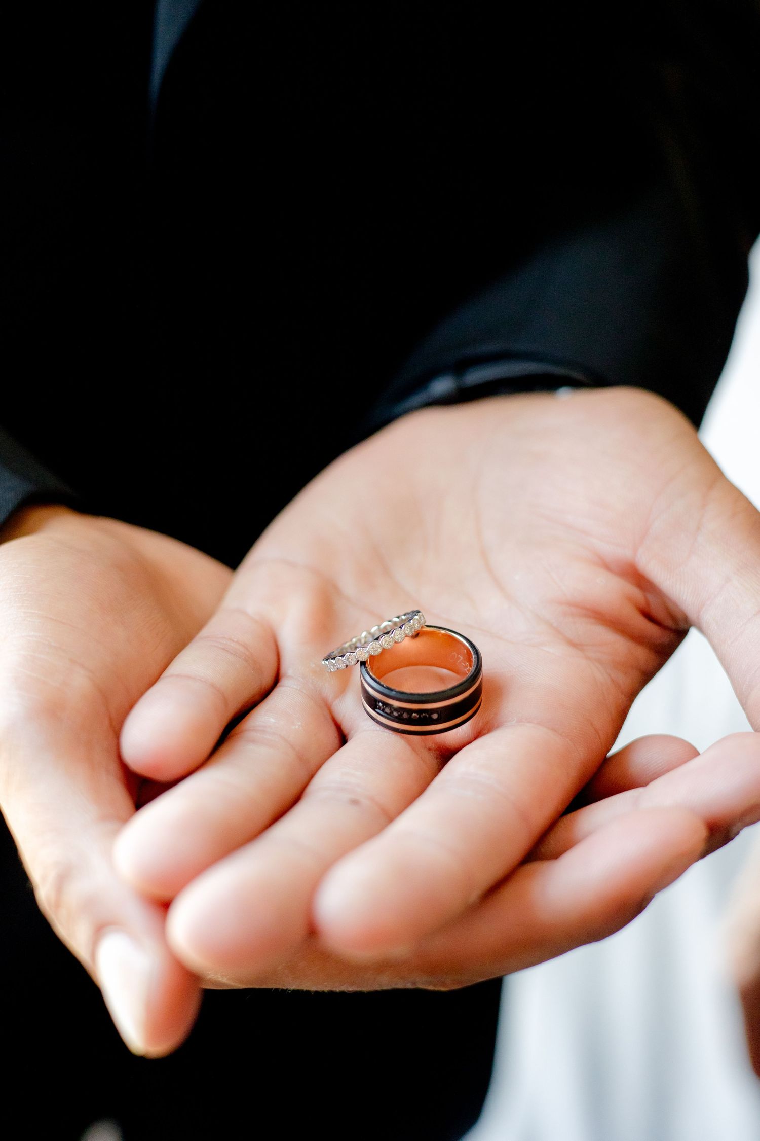 Wedding rings displayed in an open palm, showing detailed metalwork and design.