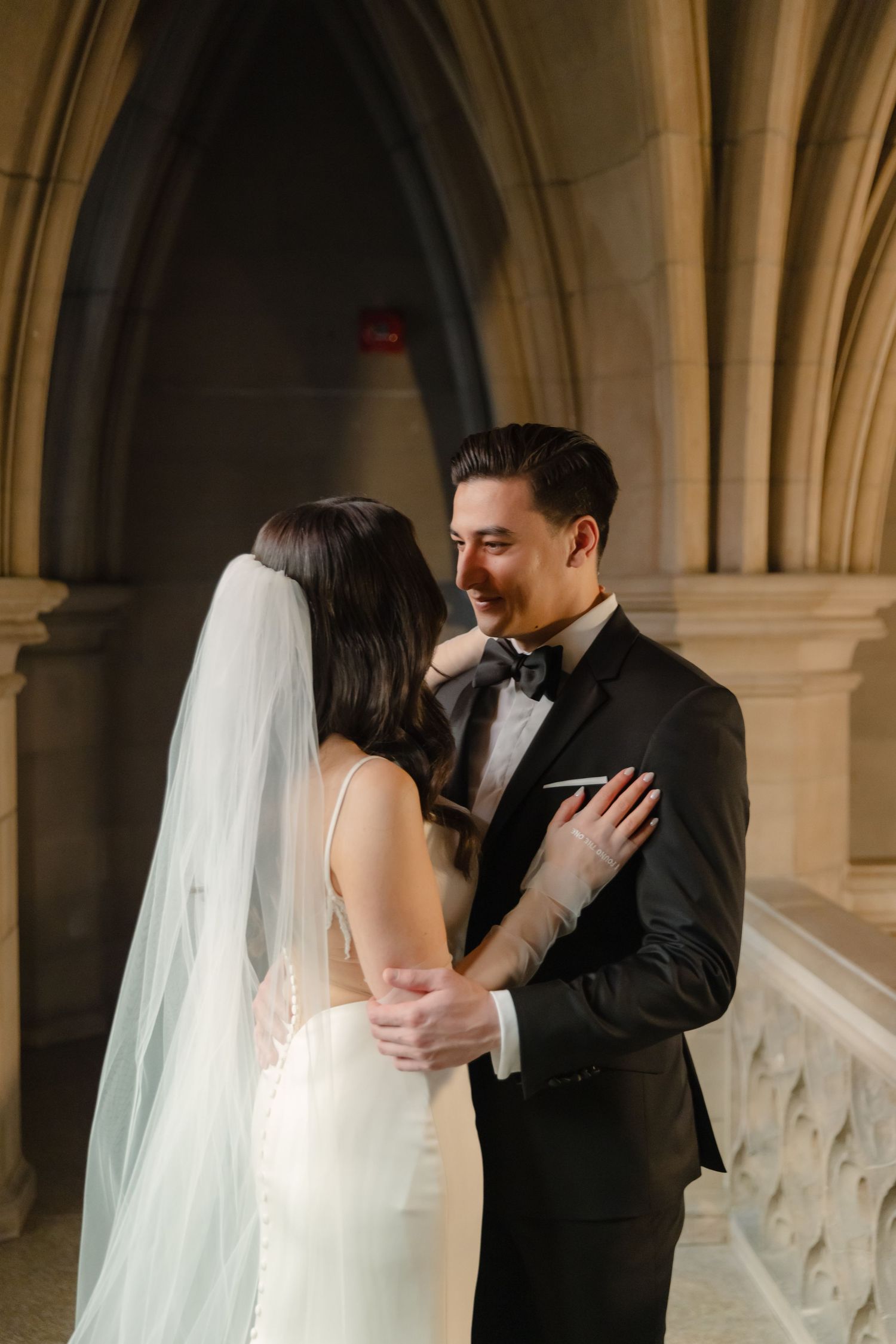 An intimate moment between newlyweds in a gothic architectural setting with stone arches.