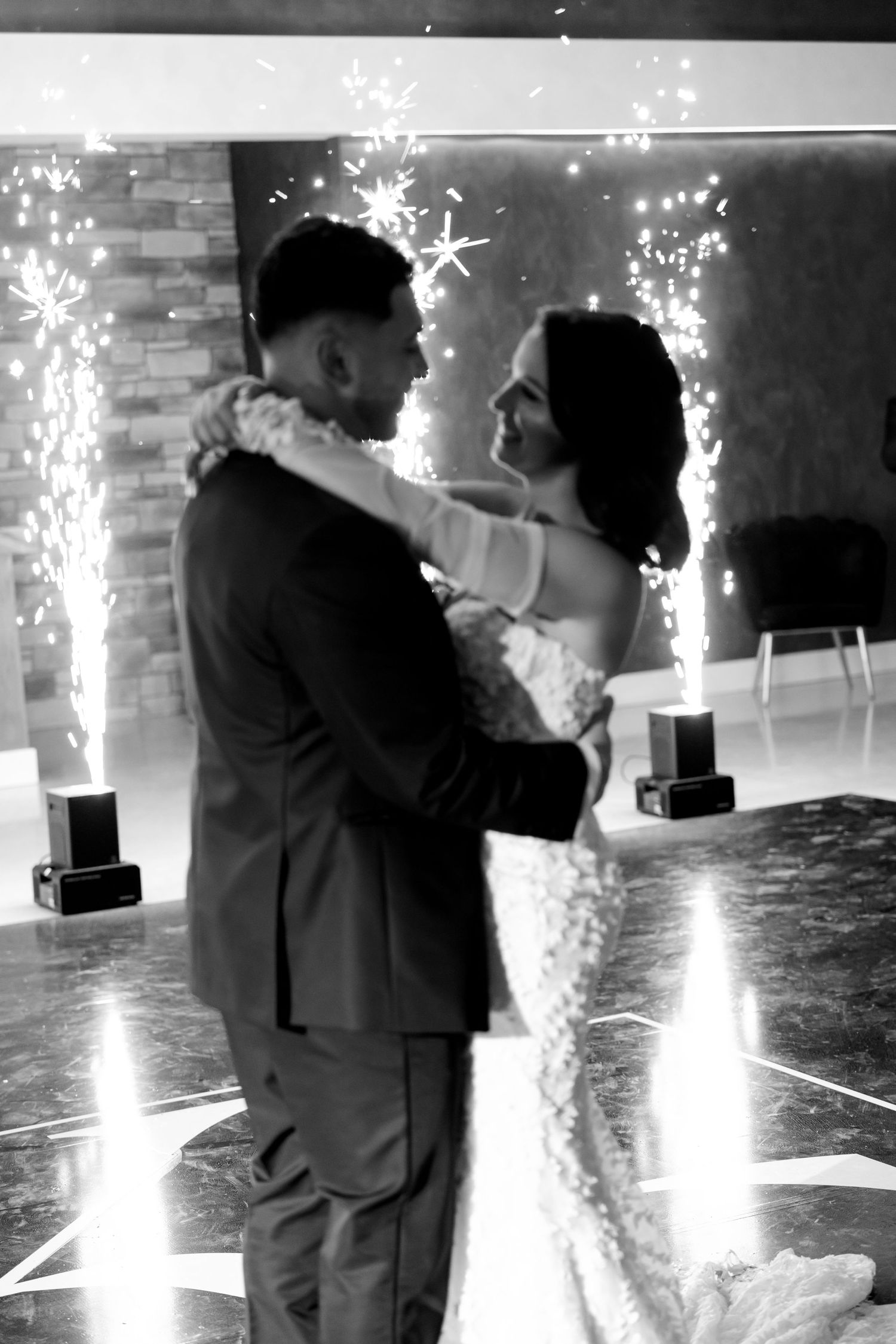 Black and white capture of couple's intimate dance moment with sparkler effects.