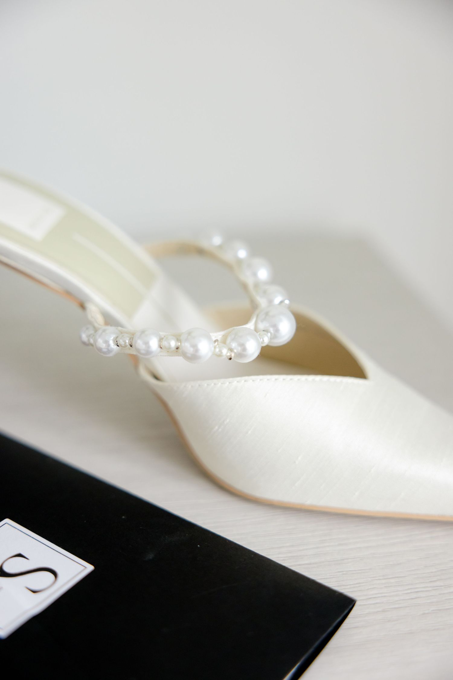 White bridal heel with delicate pearl strap detail against light background.