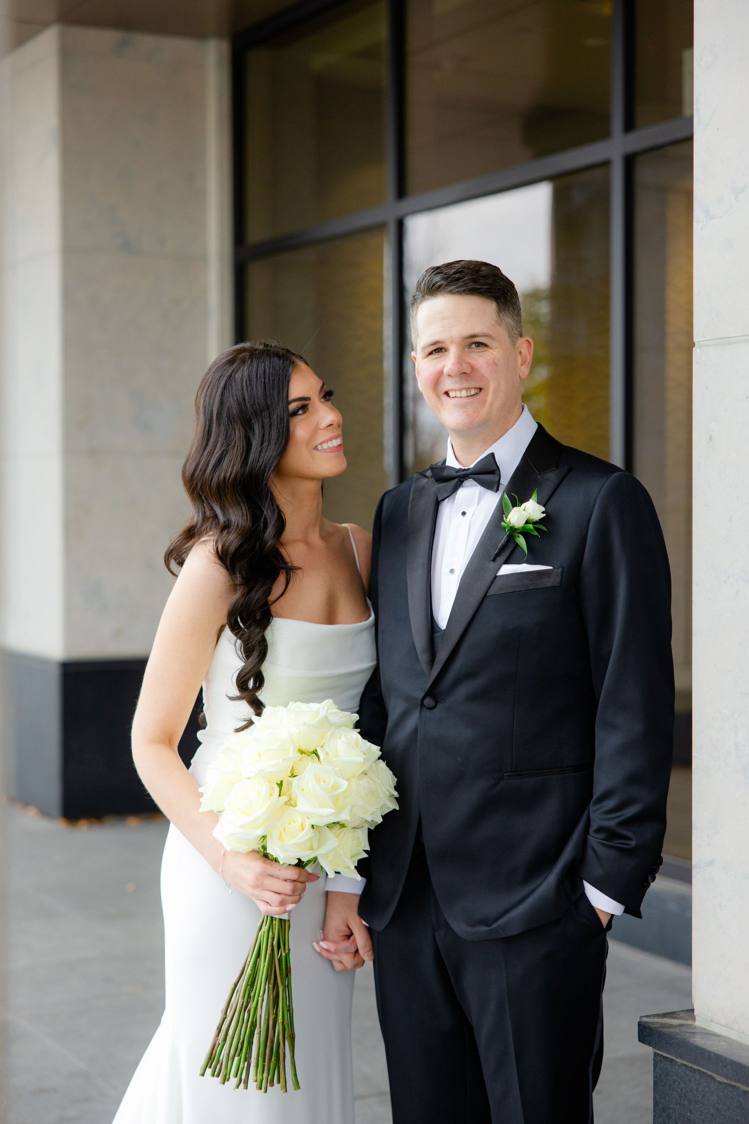 A joyful wedding portrait featuring a couple with a beautiful white flower bouquet.