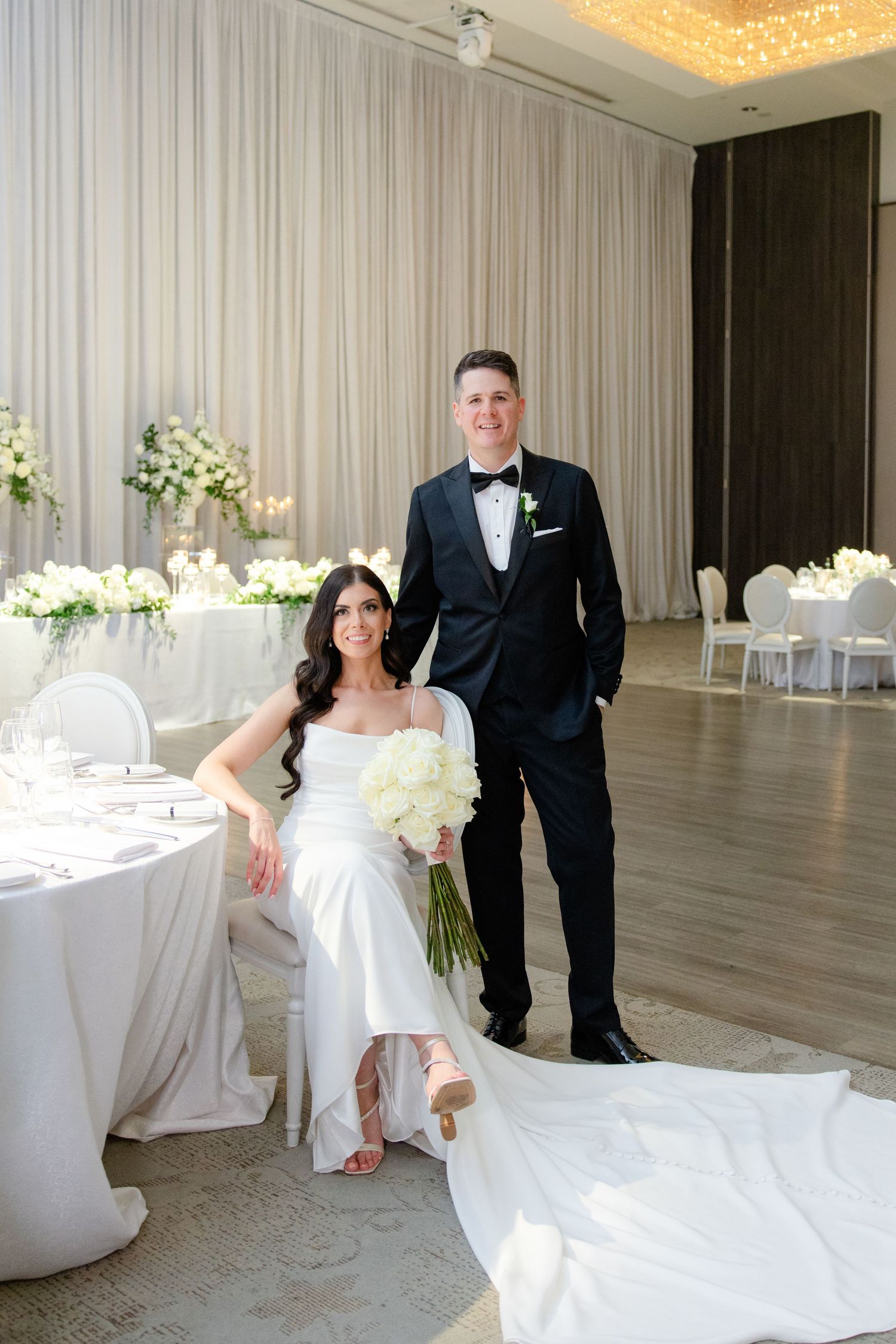 Modern wedding reception space with elegant table settings and crystal chandelier lighting.