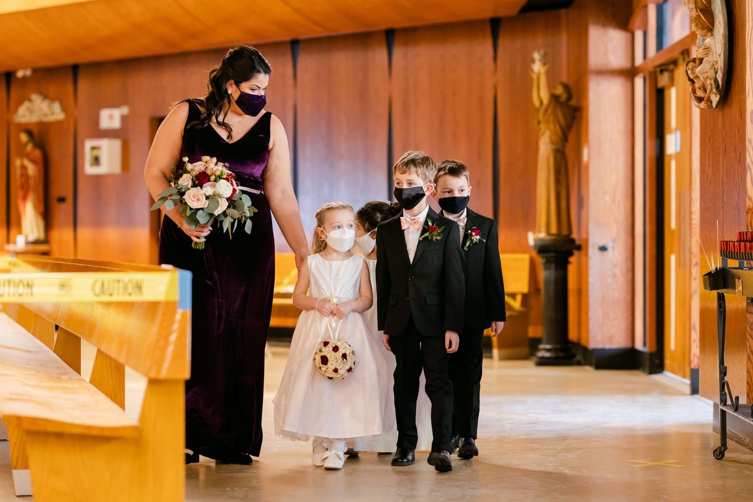 Members of a wedding party in formal attire walk down a church aisle.