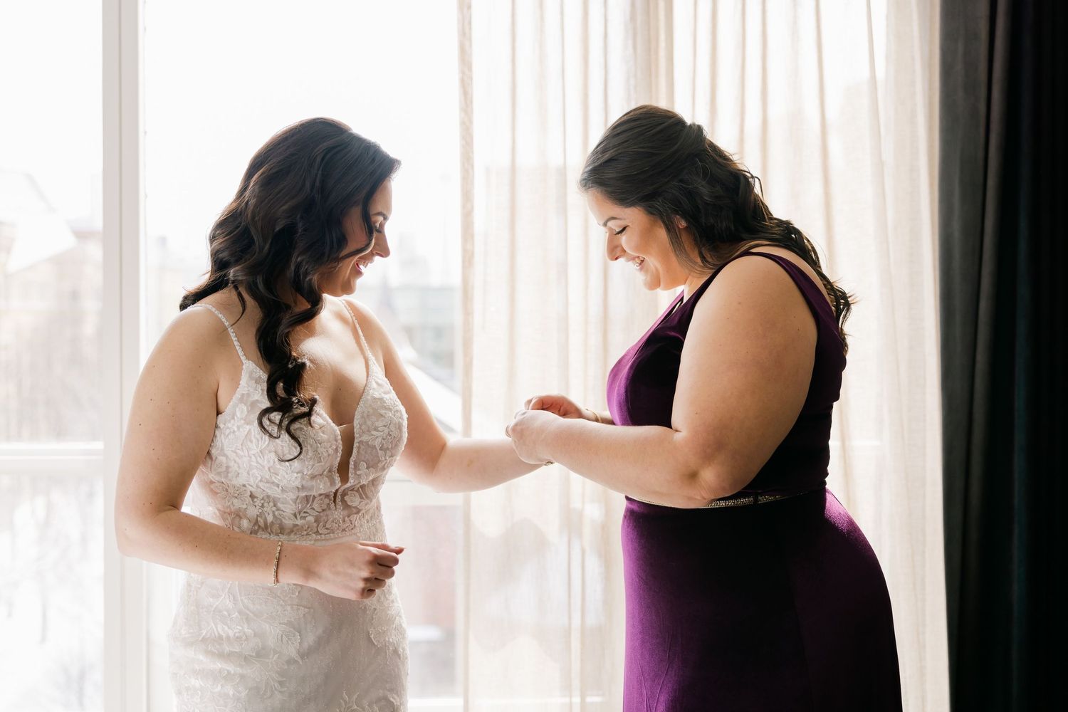 Tender moment shared during wedding preparations in front of sunlit hotel window.