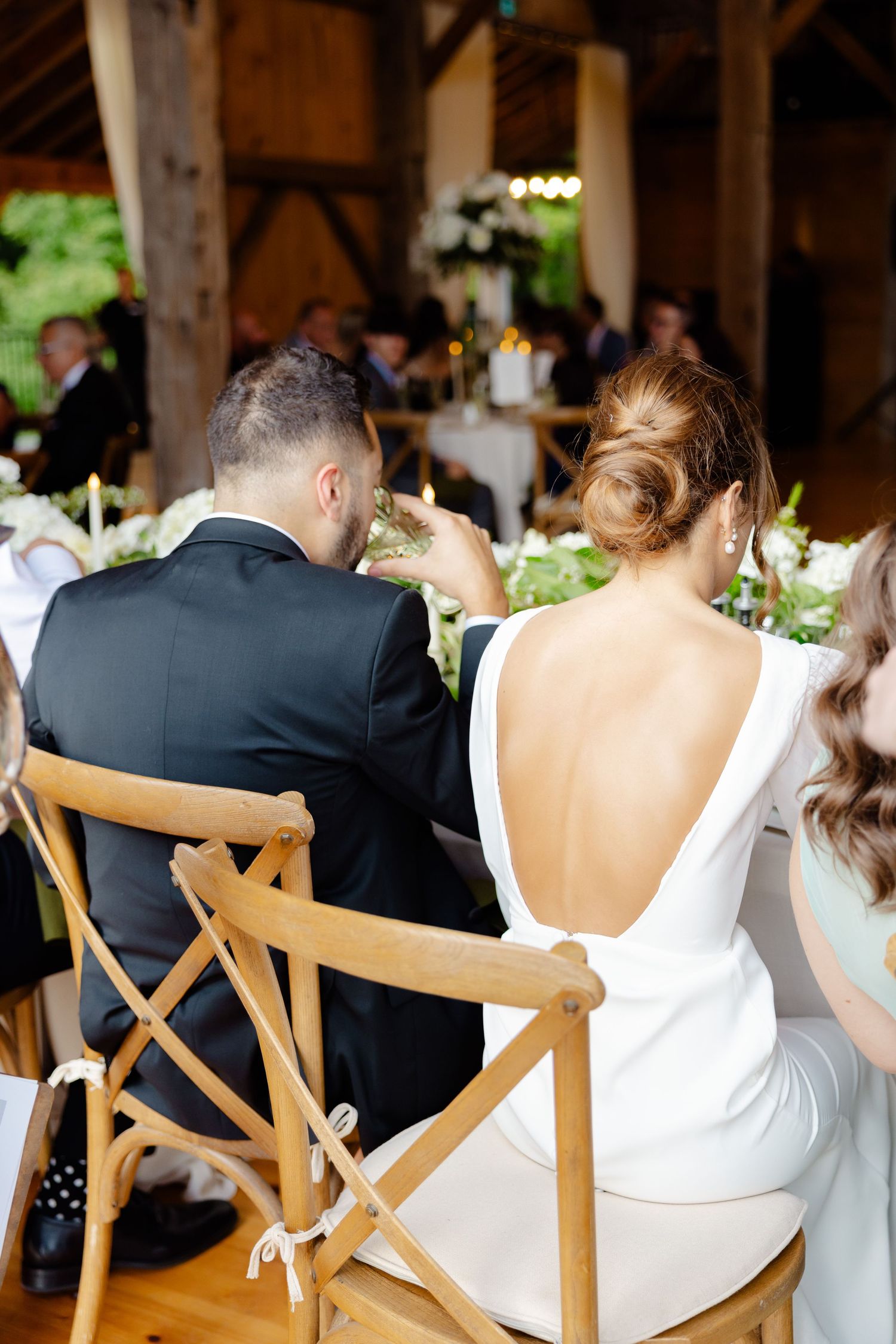 Elegant wedding reception seating with wooden chairs and rustic barn details.
