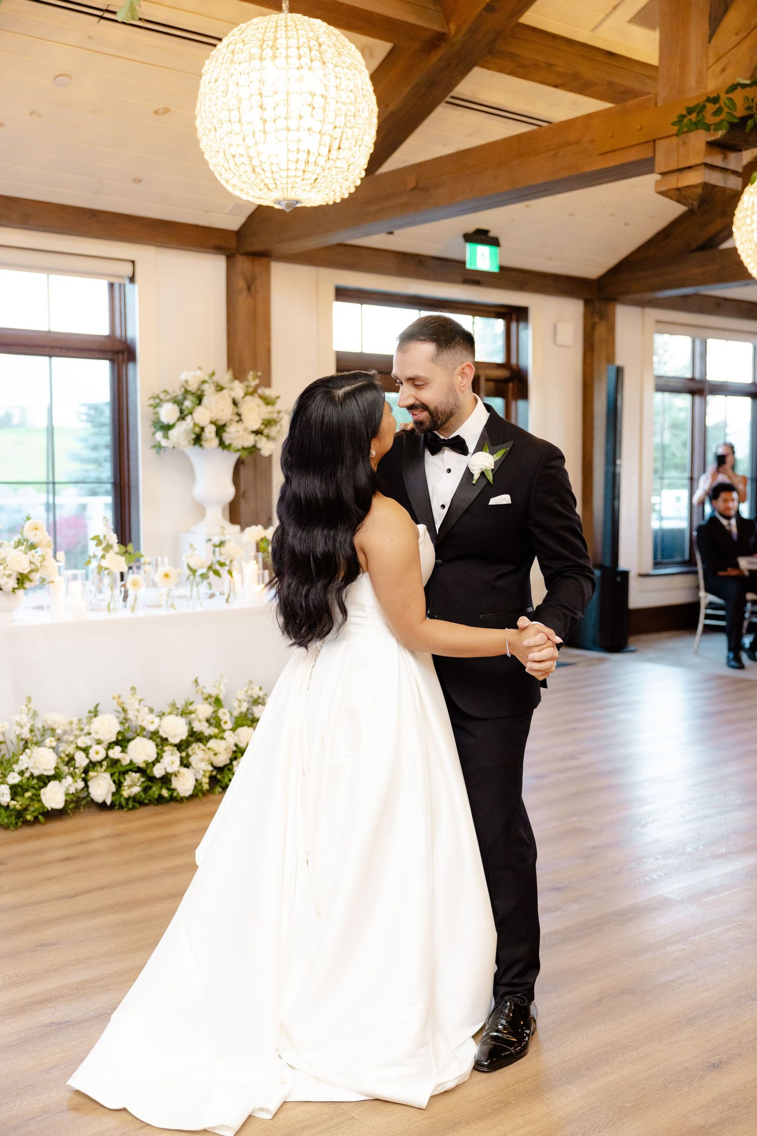 Romantic first dance moment in an elegant venue with exposed beams and chandeliers.