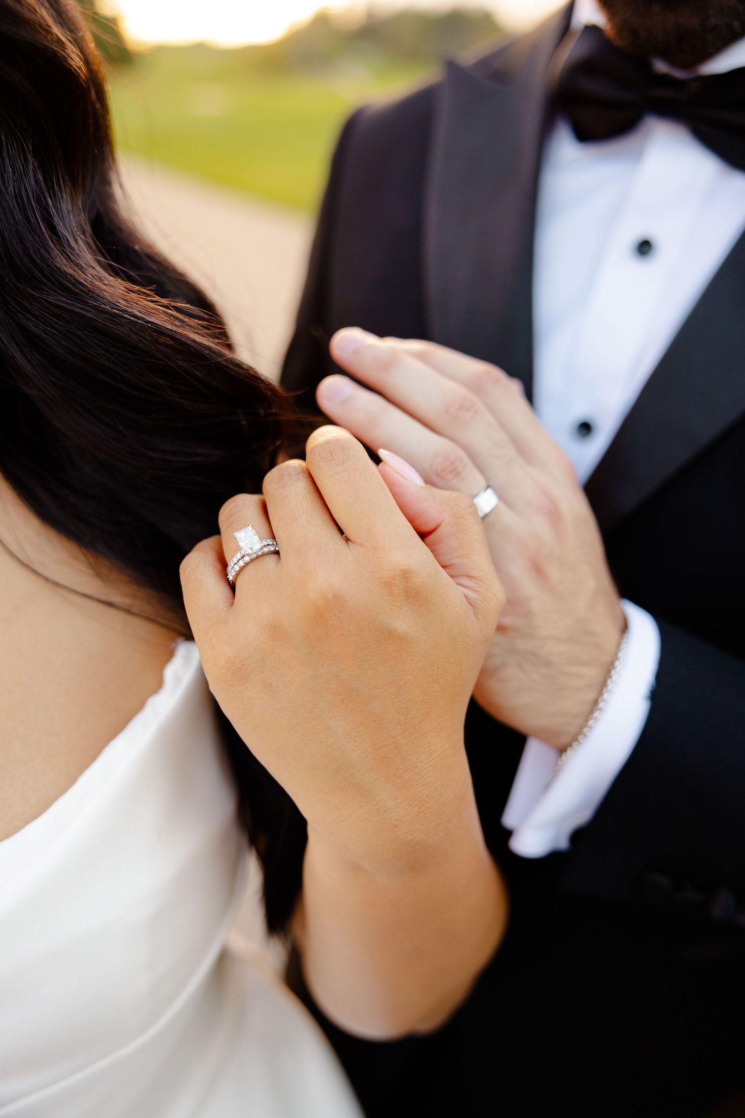 Close-up of newlyweds' hands showing wedding rings against formal attire.