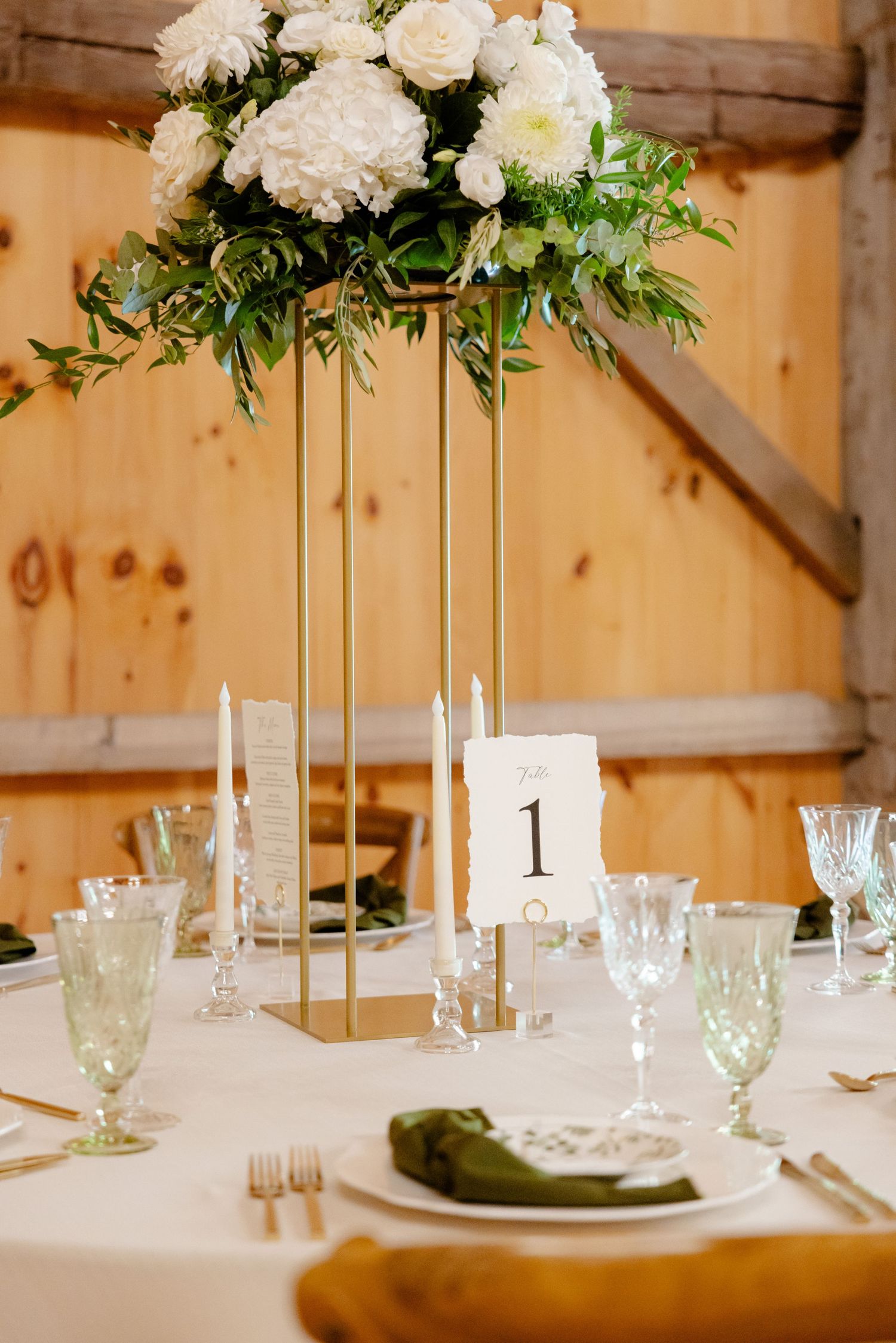 Modern table setting with tall white floral arrangement and gold geometric centerpiece stand.