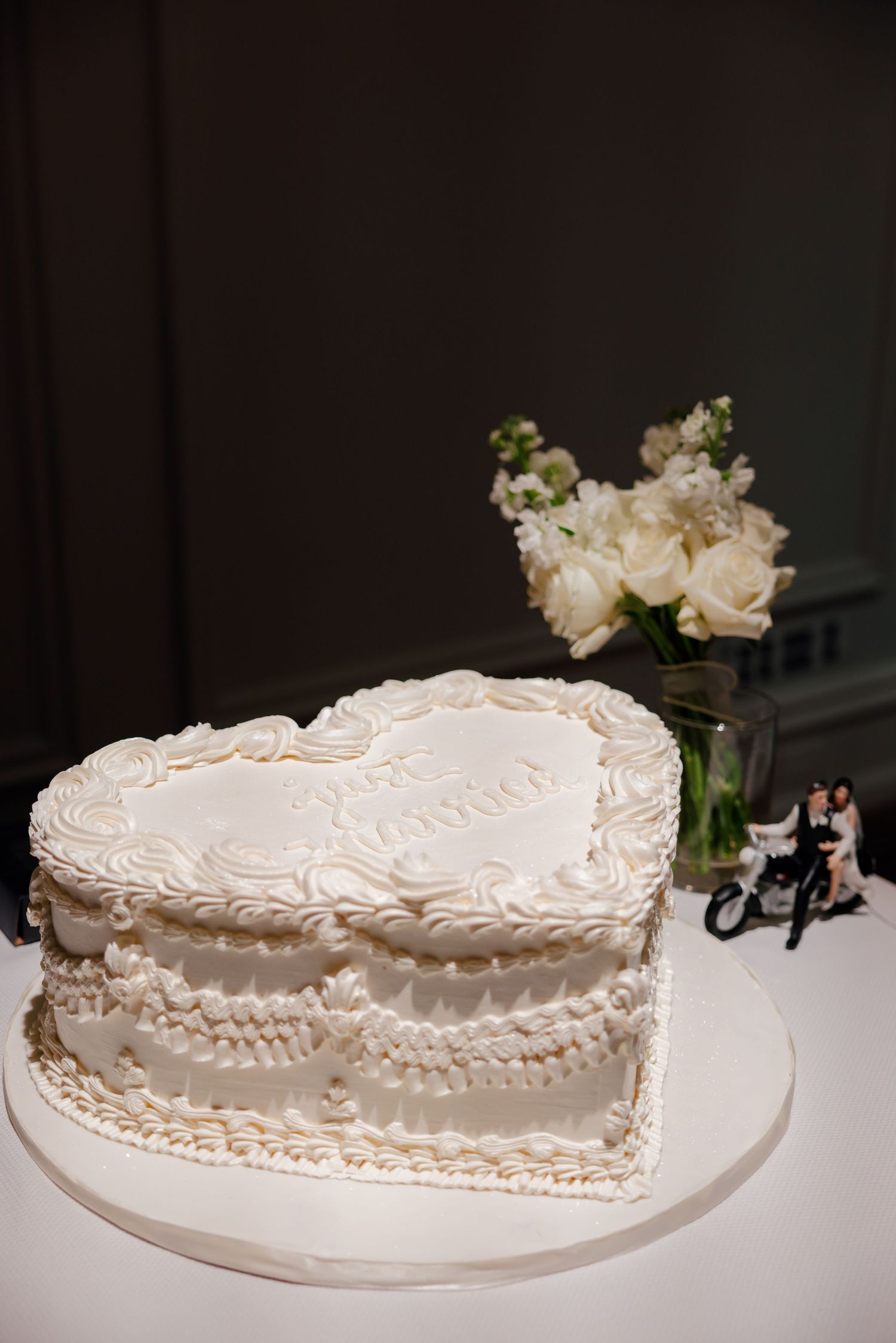 Heart-shaped white wedding cake with intricate piping details and floral decorations.