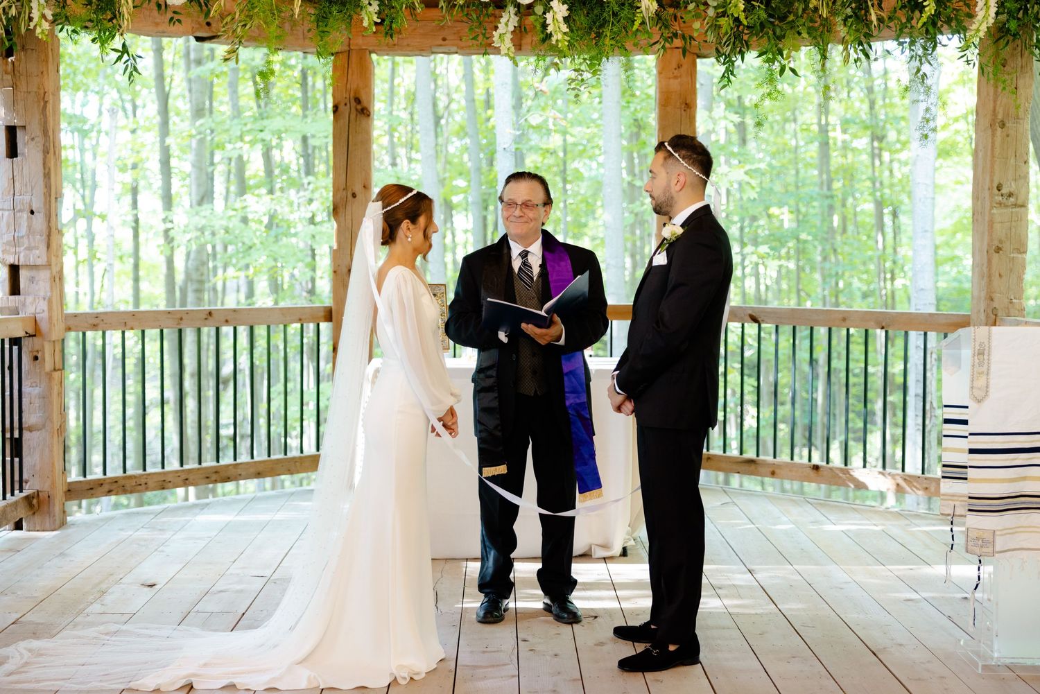 Wedding ceremony in a light-filled wooden pavilion surrounded by forest views.