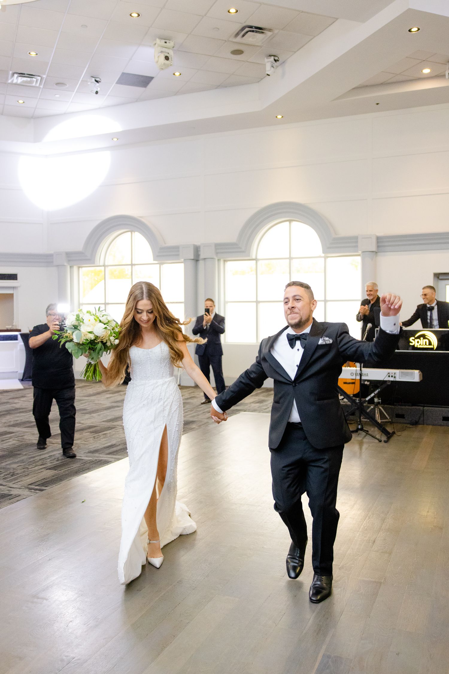 Bright ballroom wedding reception venue with arched windows and grand celebration.