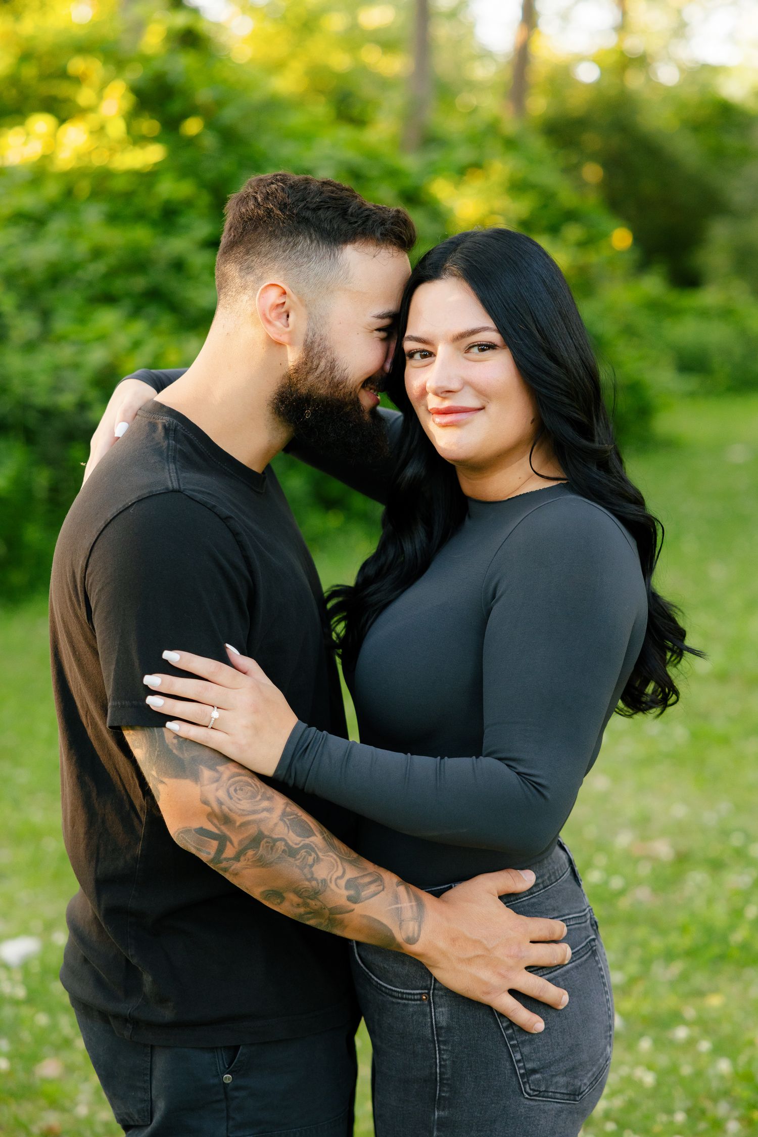 A couple shares a loving moment while posing for photos in a spring forest setting.