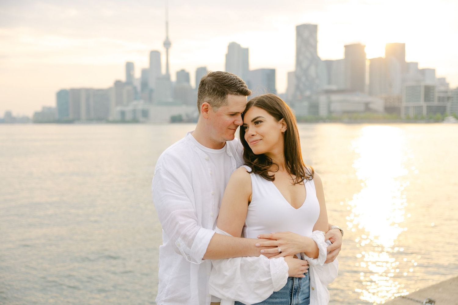 Sweet couple portrait with golden sunset and Toronto cityscape creating dreamy backdrop.