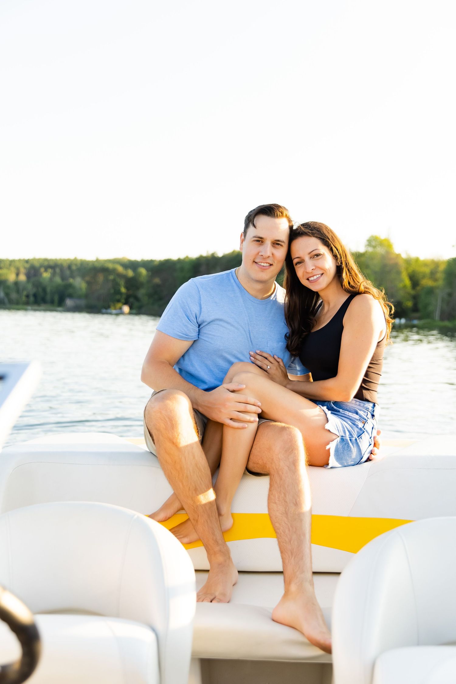 Couple sitting close together on a white boat deck during a sunny afternoon.