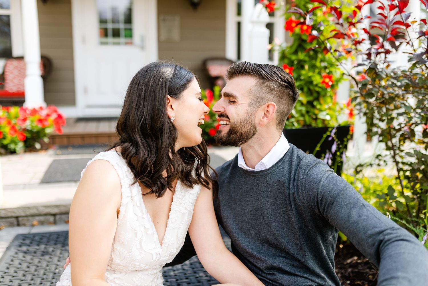 A couple shares an intimate moment while sitting on stone steps surrounded by blooming flowers.