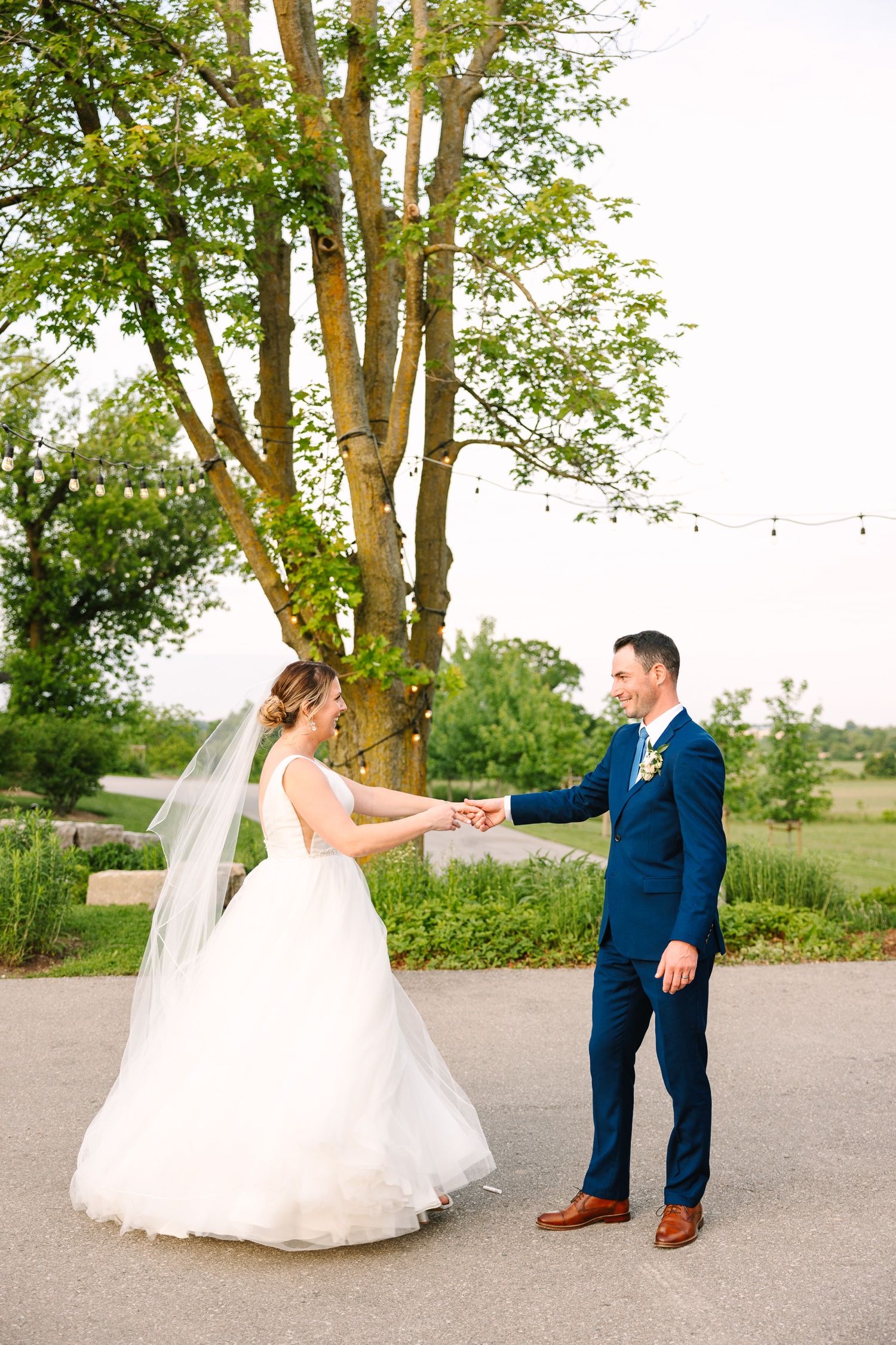 A couple dances and holds hands during their outdoor wedding photoshoot.