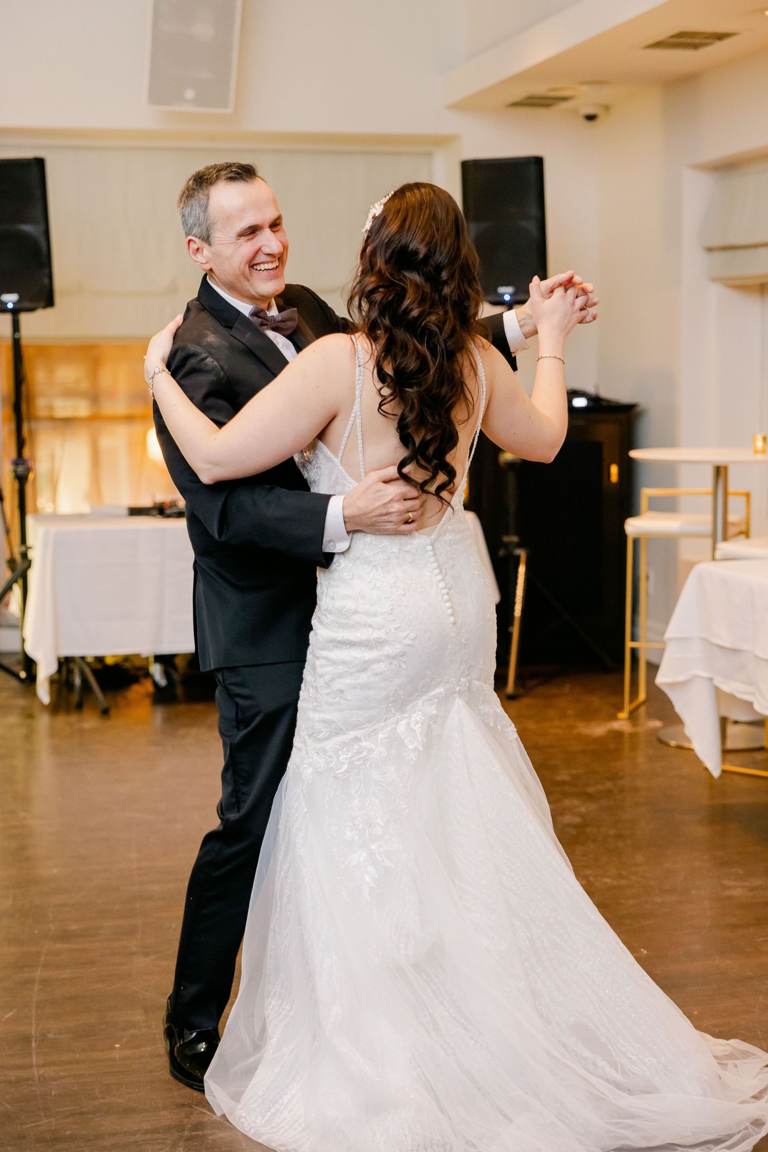 Couple shares a joyful moment during their wedding dance on hardwood floors.