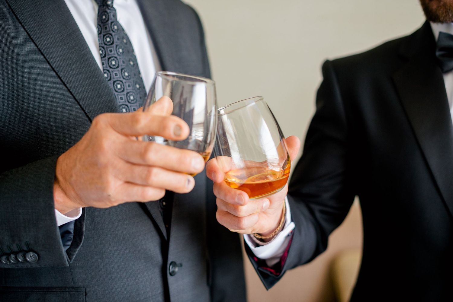 Two people in formal wear toasting with glasses of whiskey.