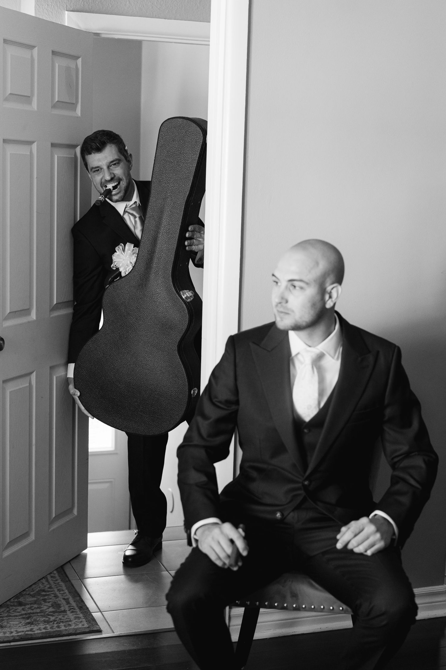 Black and white image of wedding preparation with guitar case and formal attire.