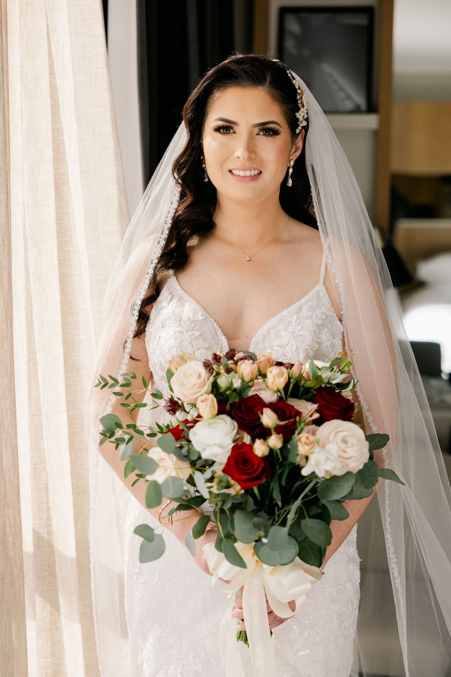 Radiant bridal portrait featuring intricate lace gown and romantic mixed flower bouquet.
