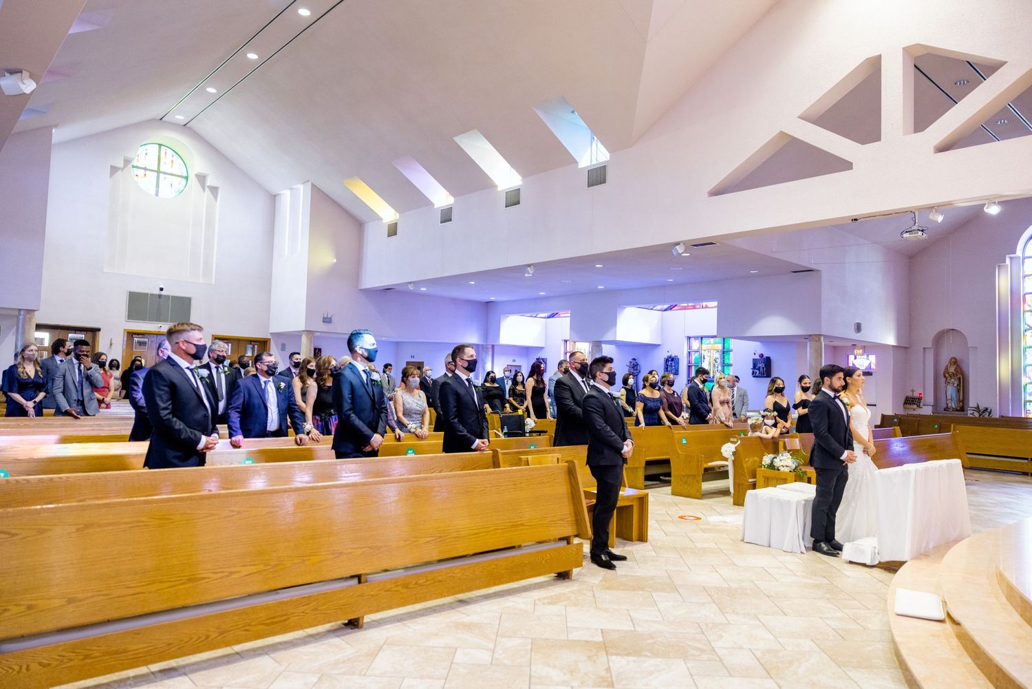 Wide shot of a wedding ceremony in a modern church with vaulted ceilings and natural light.