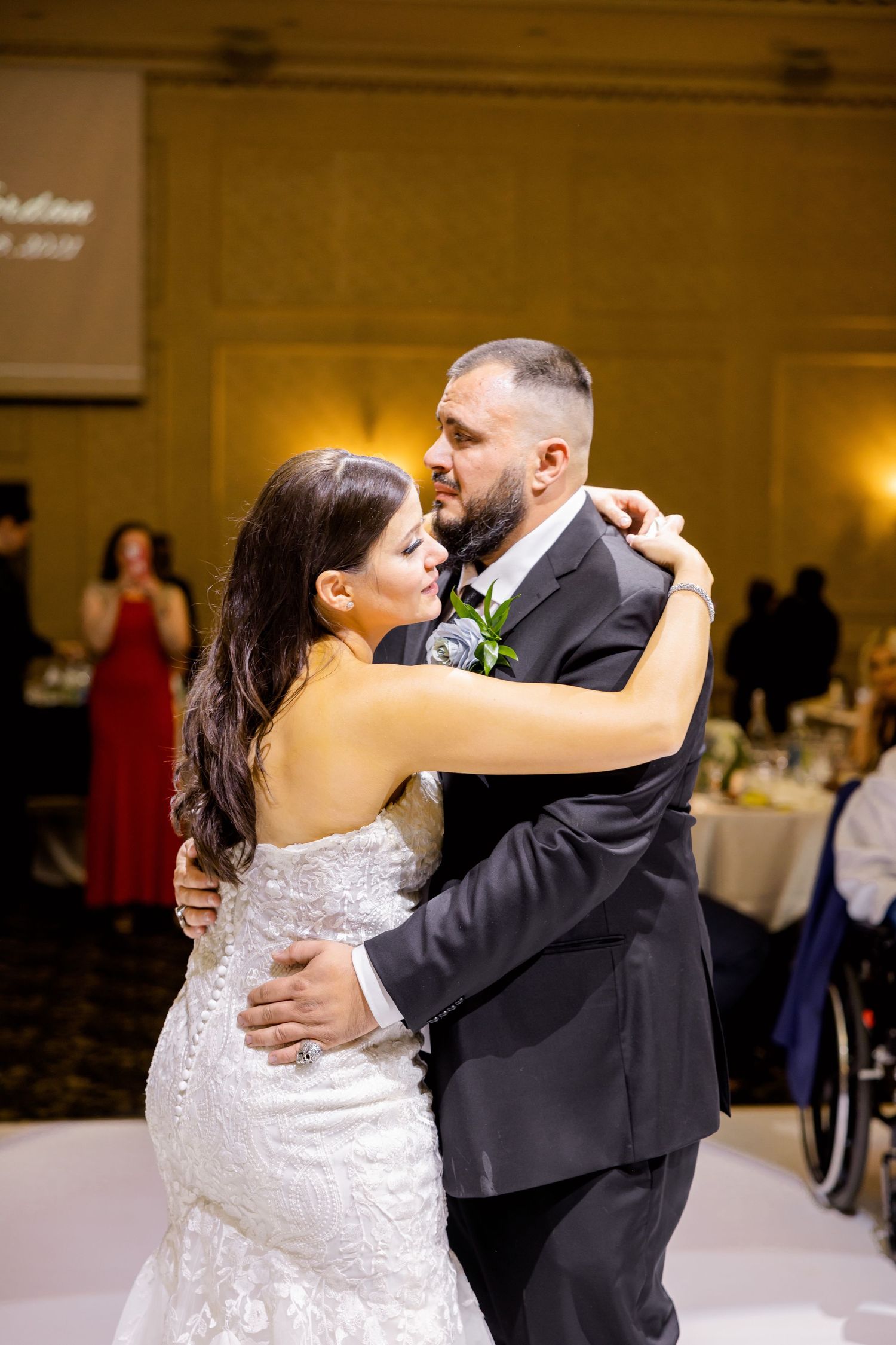 A tender embrace during a wedding dance under warm lighting in an elegant ballroom.