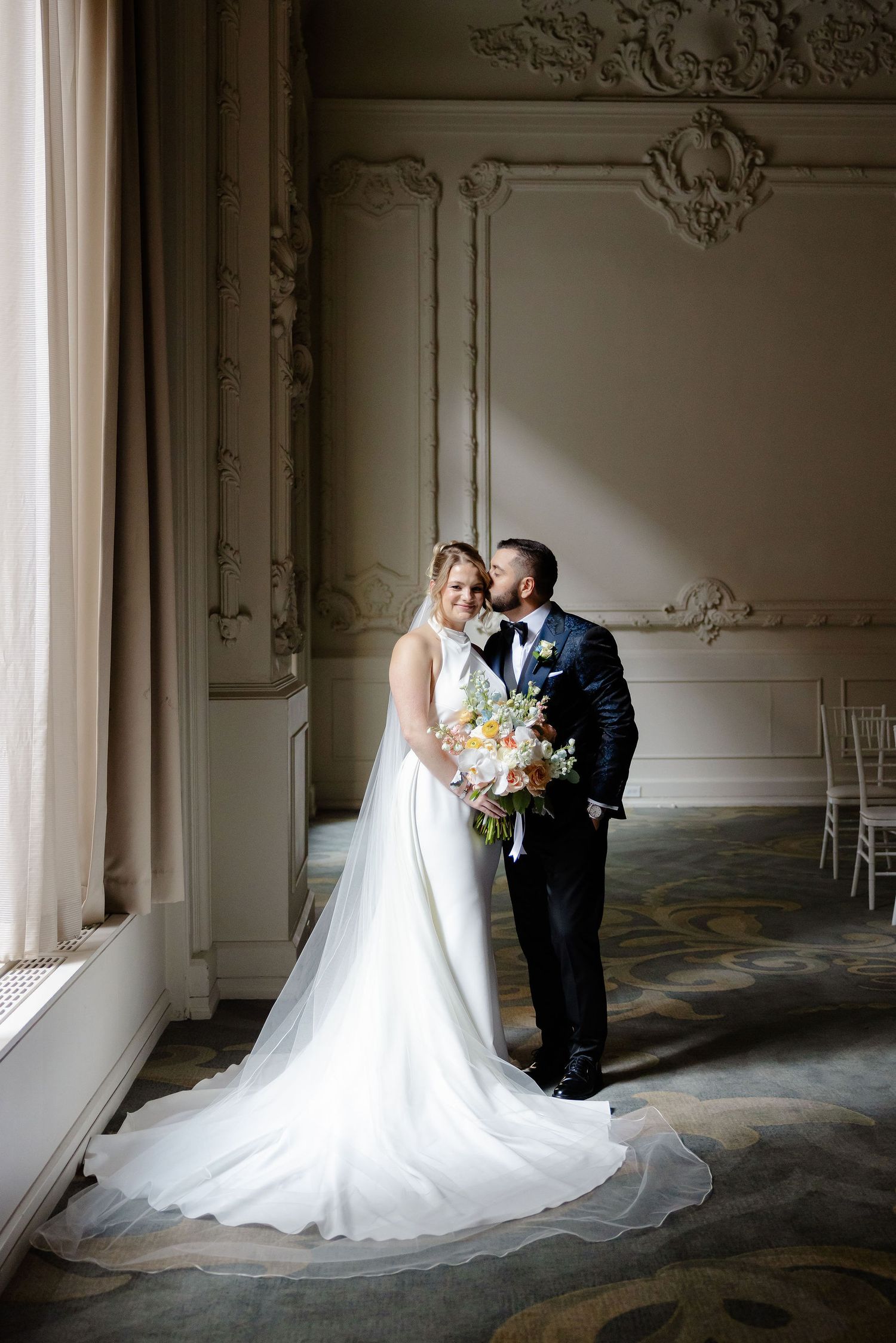 Elegant wedding portraits captured in a historic venue with decorative wall moldings and natural lighting.
