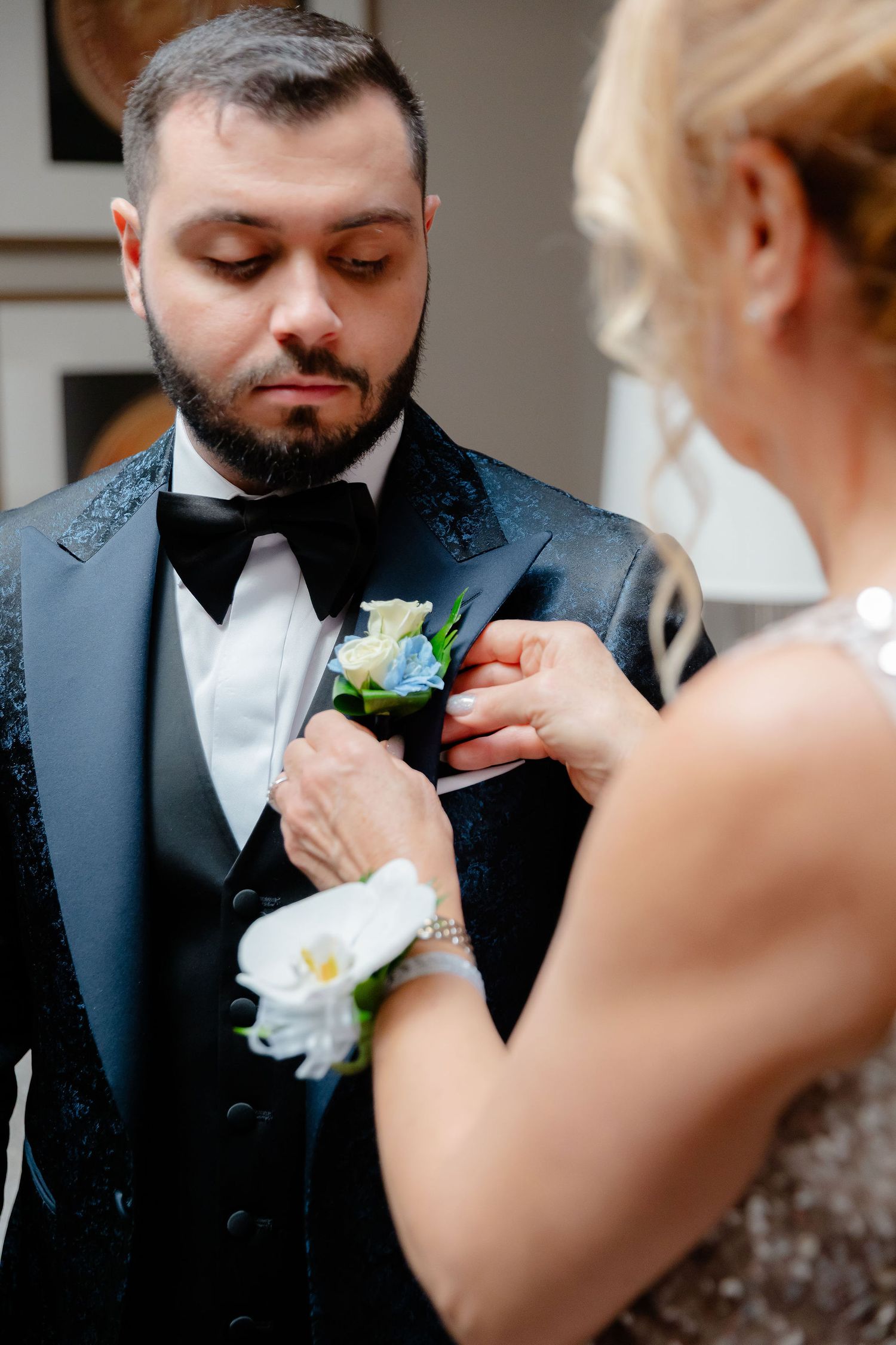 Close-up shots of someone having a white floral boutonniere pinned to their navy suit lapel.