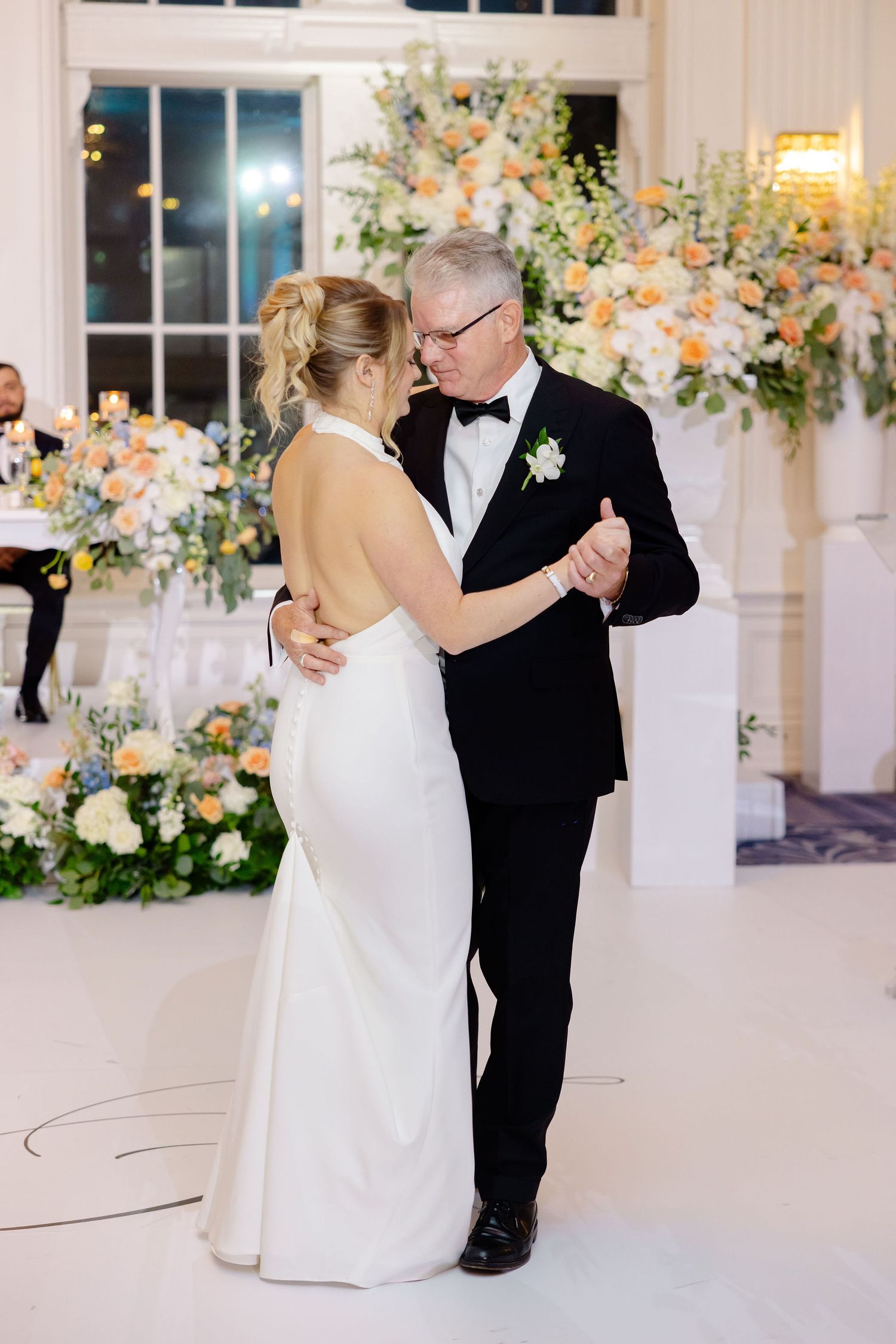 Elegant wedding reception venue decorated with peach and white floral arrangements.