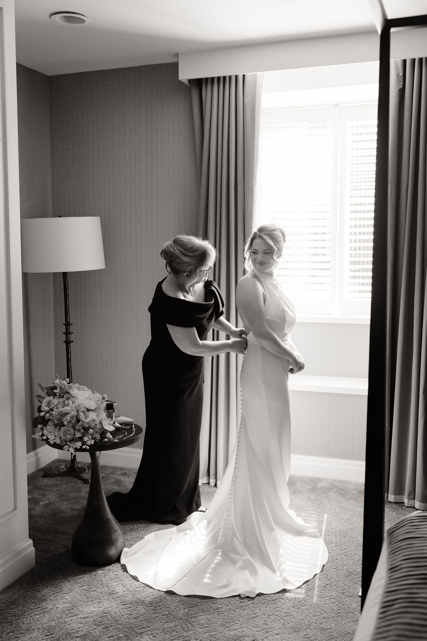 Artistic series of a flowing white wedding gown against dark curtains in natural window light.