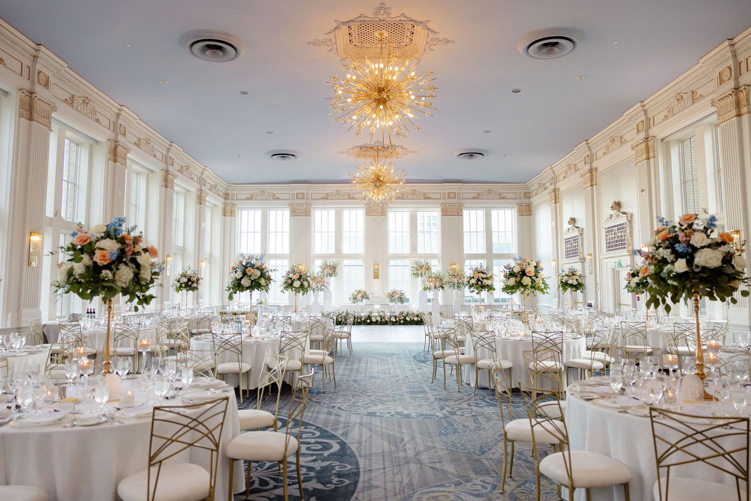 Luxurious white wedding reception ballroom with crystal chandeliers and elegant table settings.