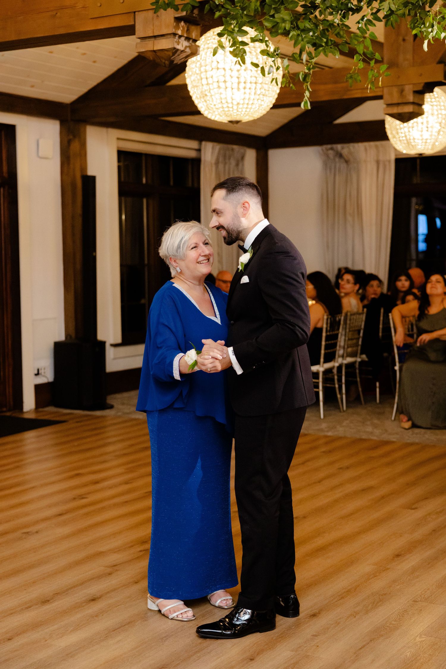 Wedding dance between two people in a beautifully decorated reception hall with chandelier lighting.
