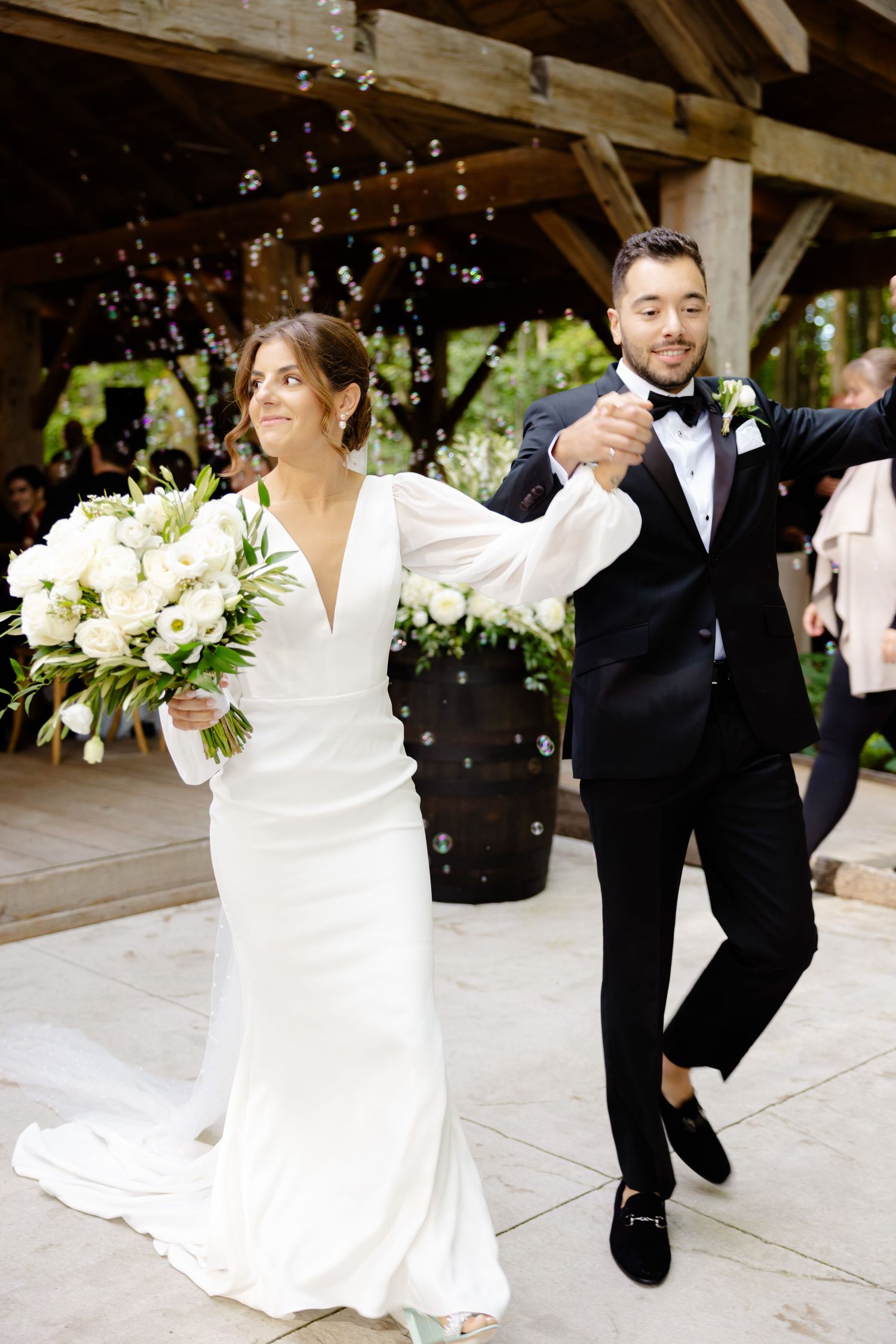 Joyful wedding couple dancing and celebrating in a rustic venue decorated with fairy lights.