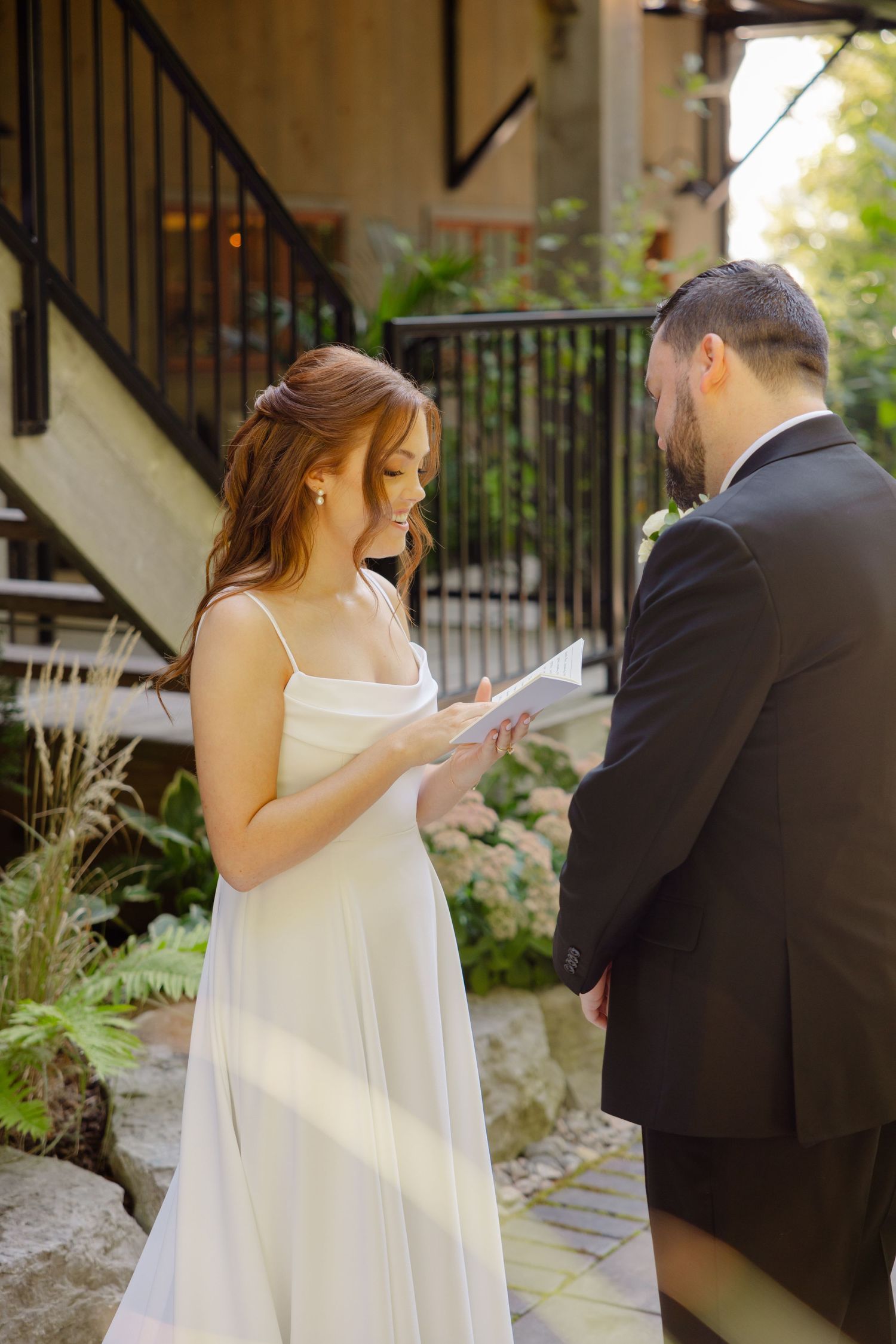 Intimate wedding moment captured under stairs with natural garden surroundings.