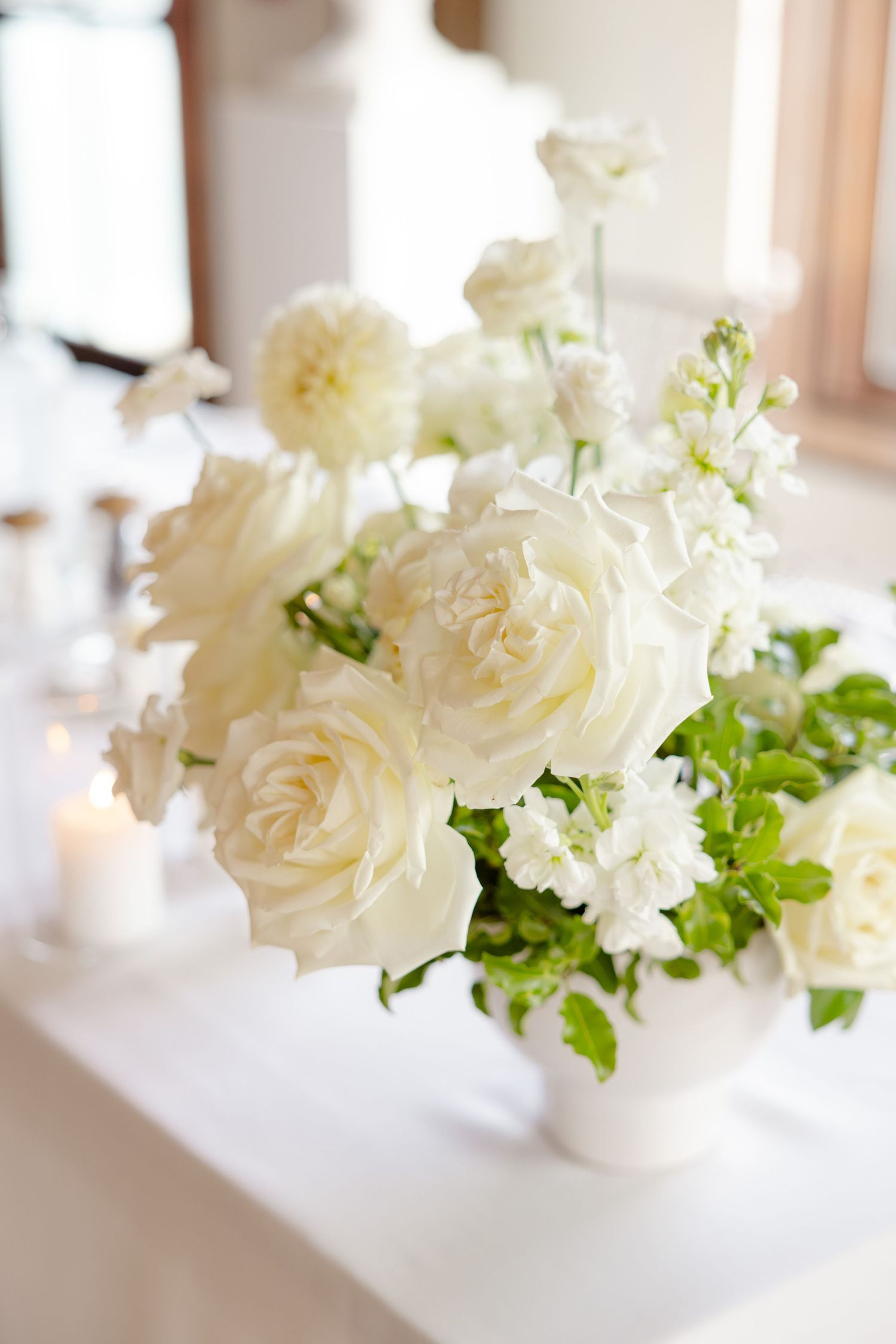 White roses and delicate flowers arranged in an elegant centerpiece display.