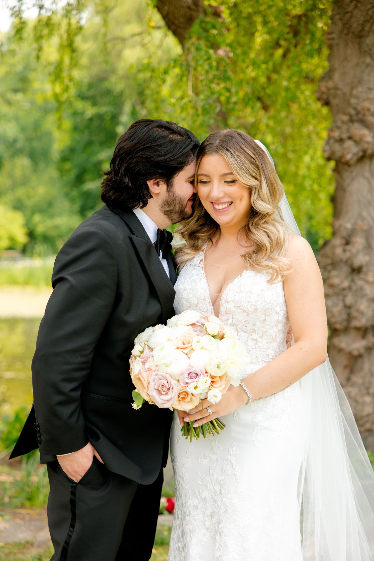 Tender wedding moment captured in garden setting with bride holding pink and white rose bouquet.