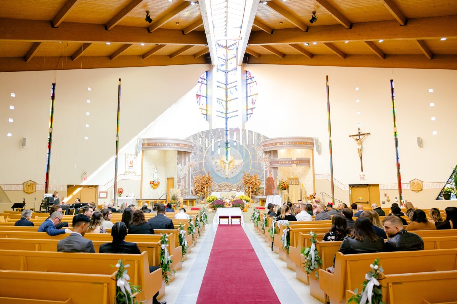 Modern church interior with wooden beams and chandelier set for wedding ceremony.