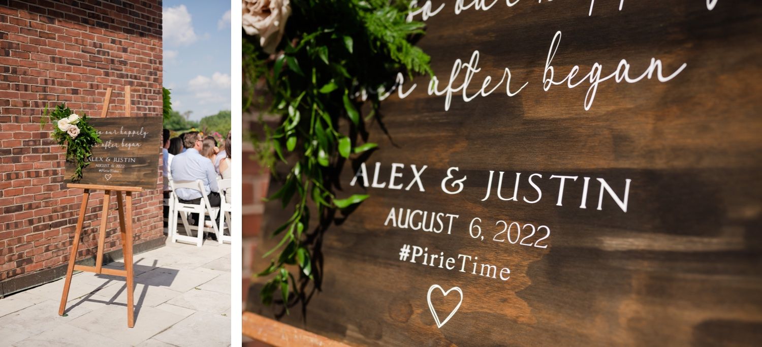 Wedding signage with names Alex & Justin displayed on rustic wooden board with greenery.