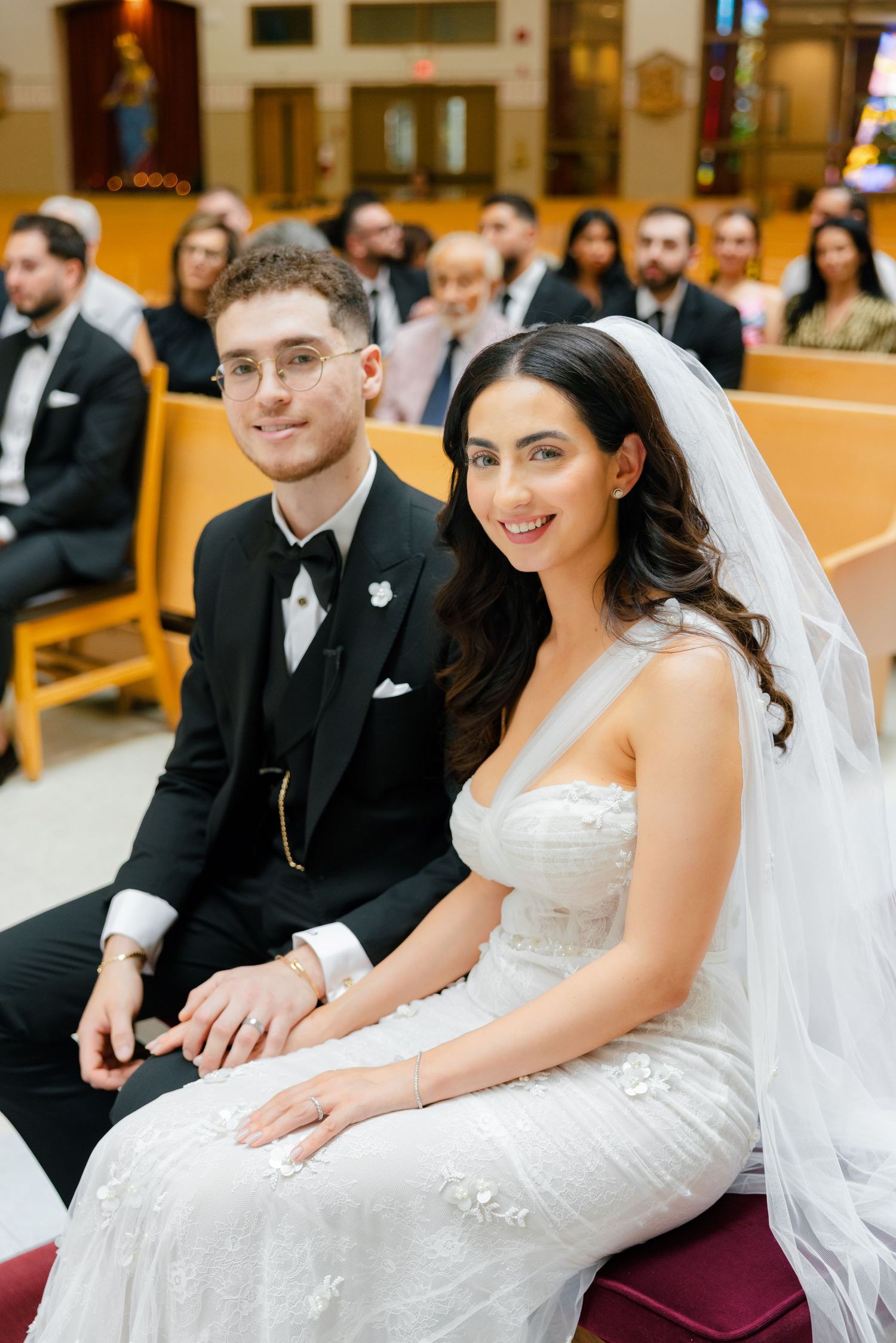 A couple sits together during their wedding ceremony in a church sanctuary.