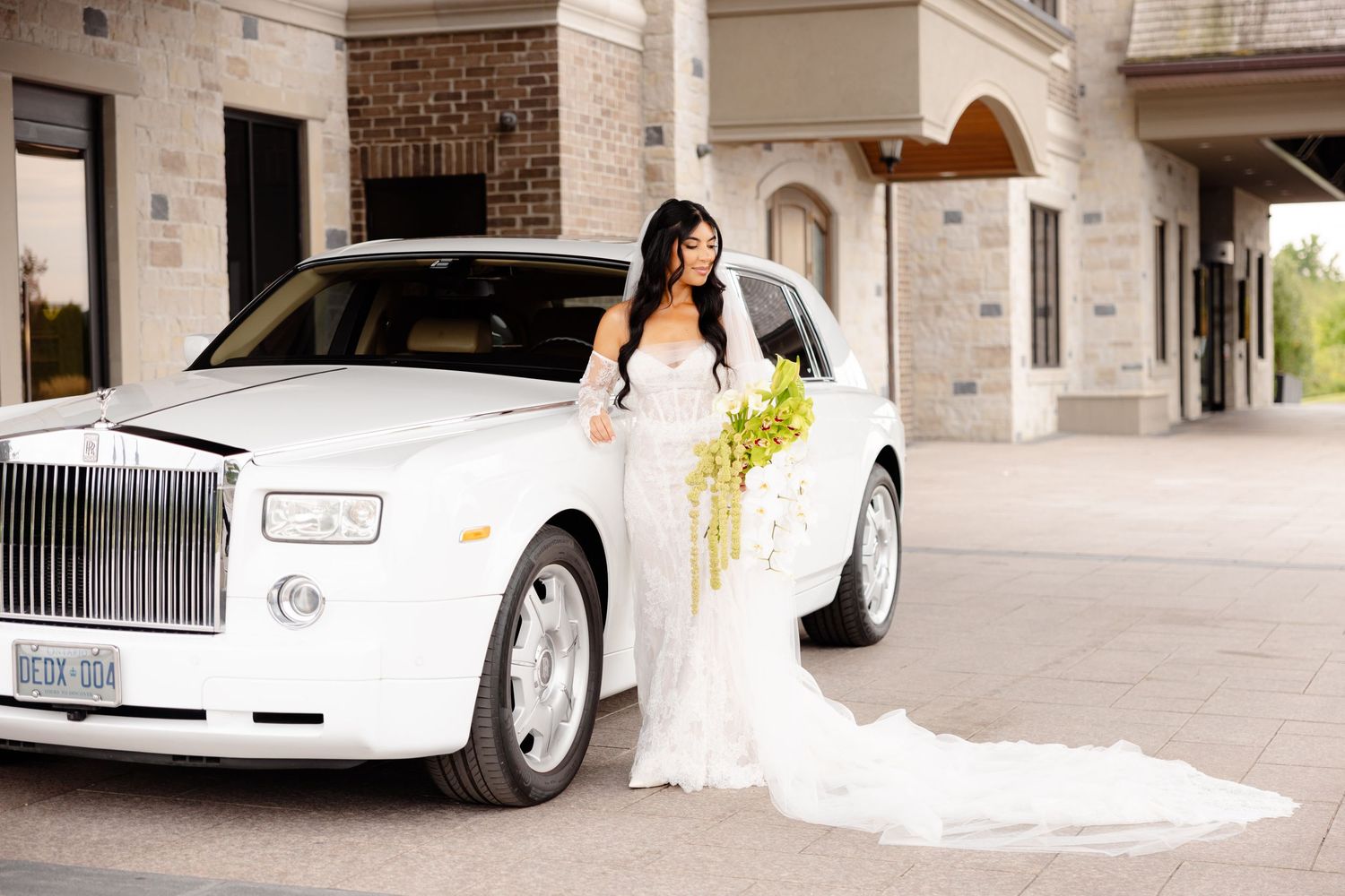 Luxury white wedding car parked in front of stone building entrance.