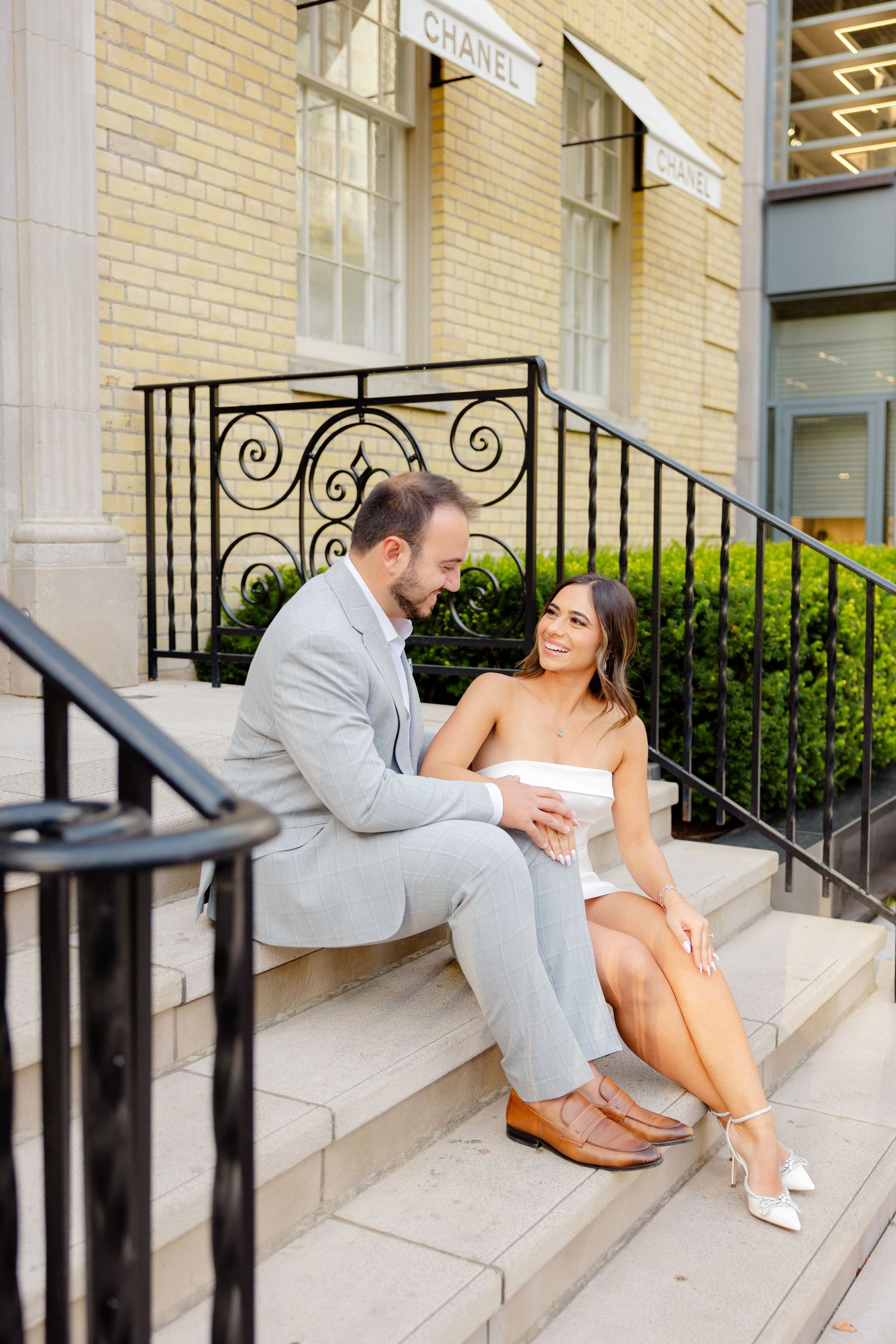 An intimate photograph on the steps of a Chanel store featuring elegant formal attire.
