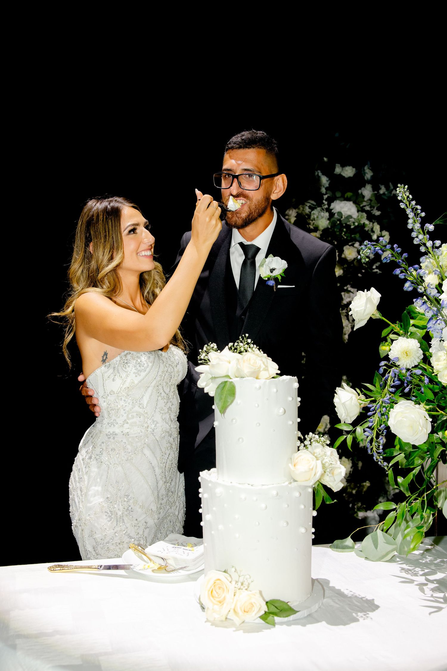 Bride feeding cake to groom during traditional wedding cake cutting ceremony.