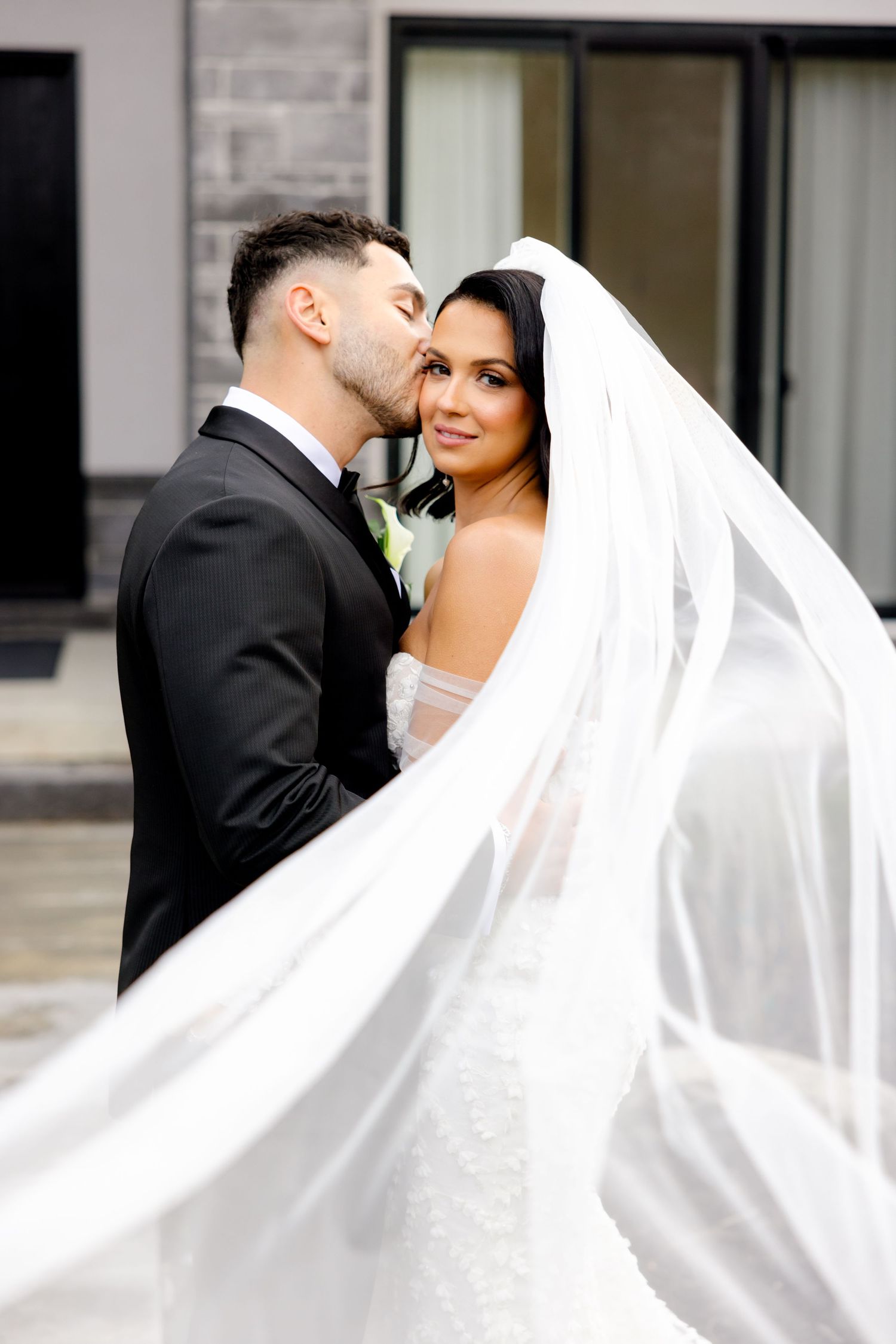 Wedding couple shares an intimate moment as the bride's veil catches the light breeze.