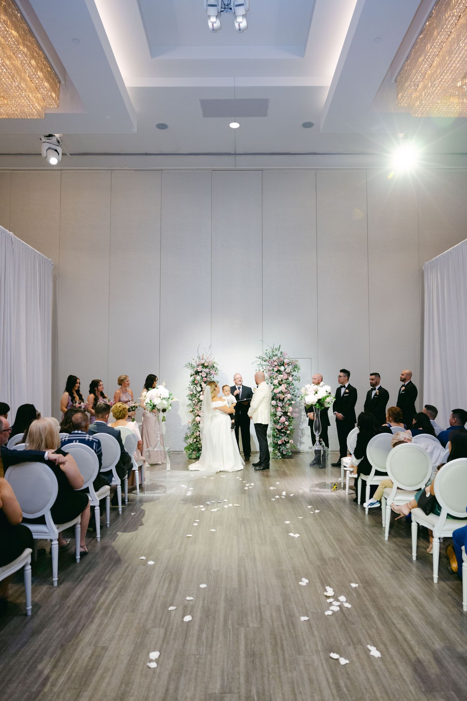 Wedding ceremony venue with white chairs and floral arch at the altar.