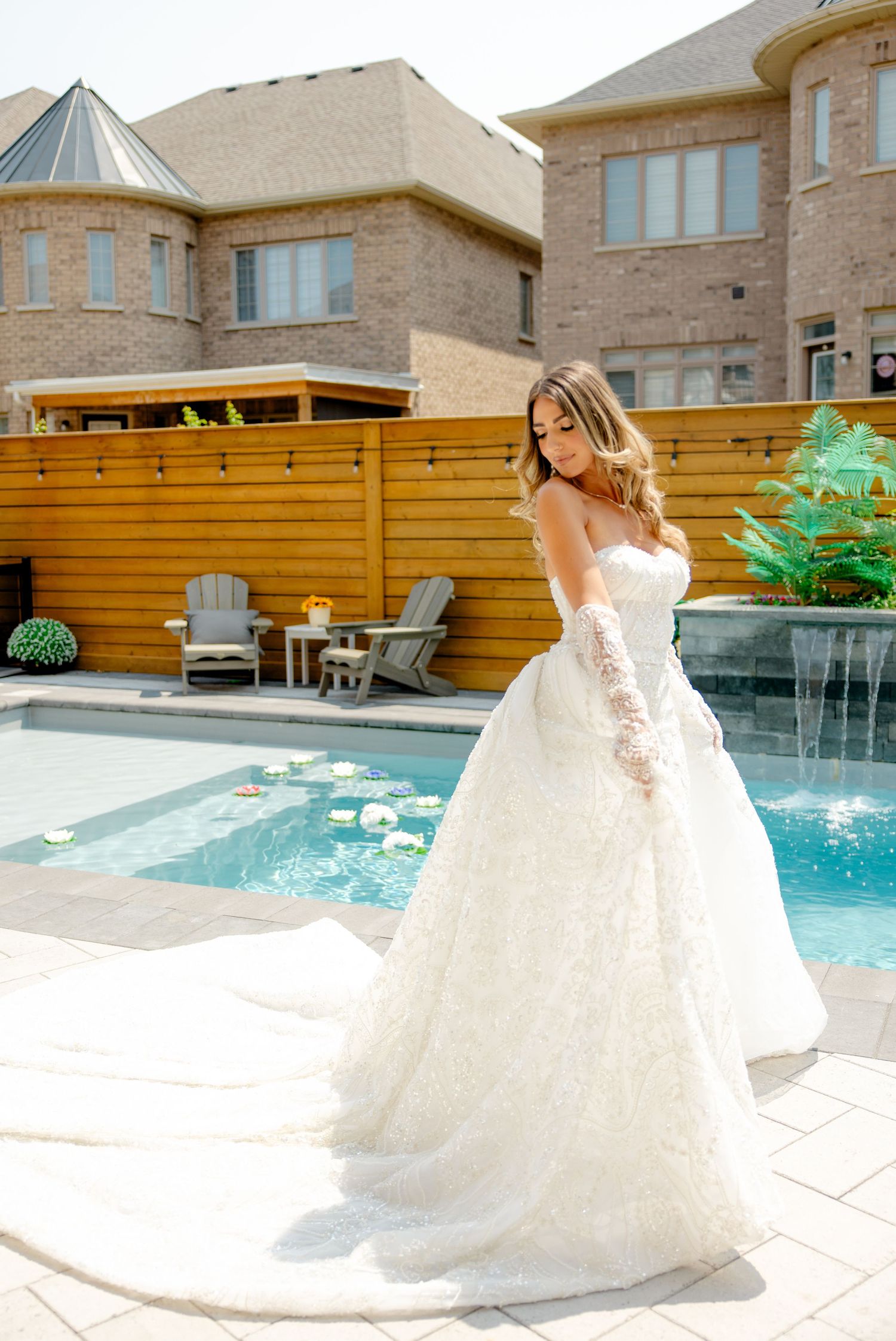 An elegant bridal gown with a flowing train captured in an outdoor poolside setting.