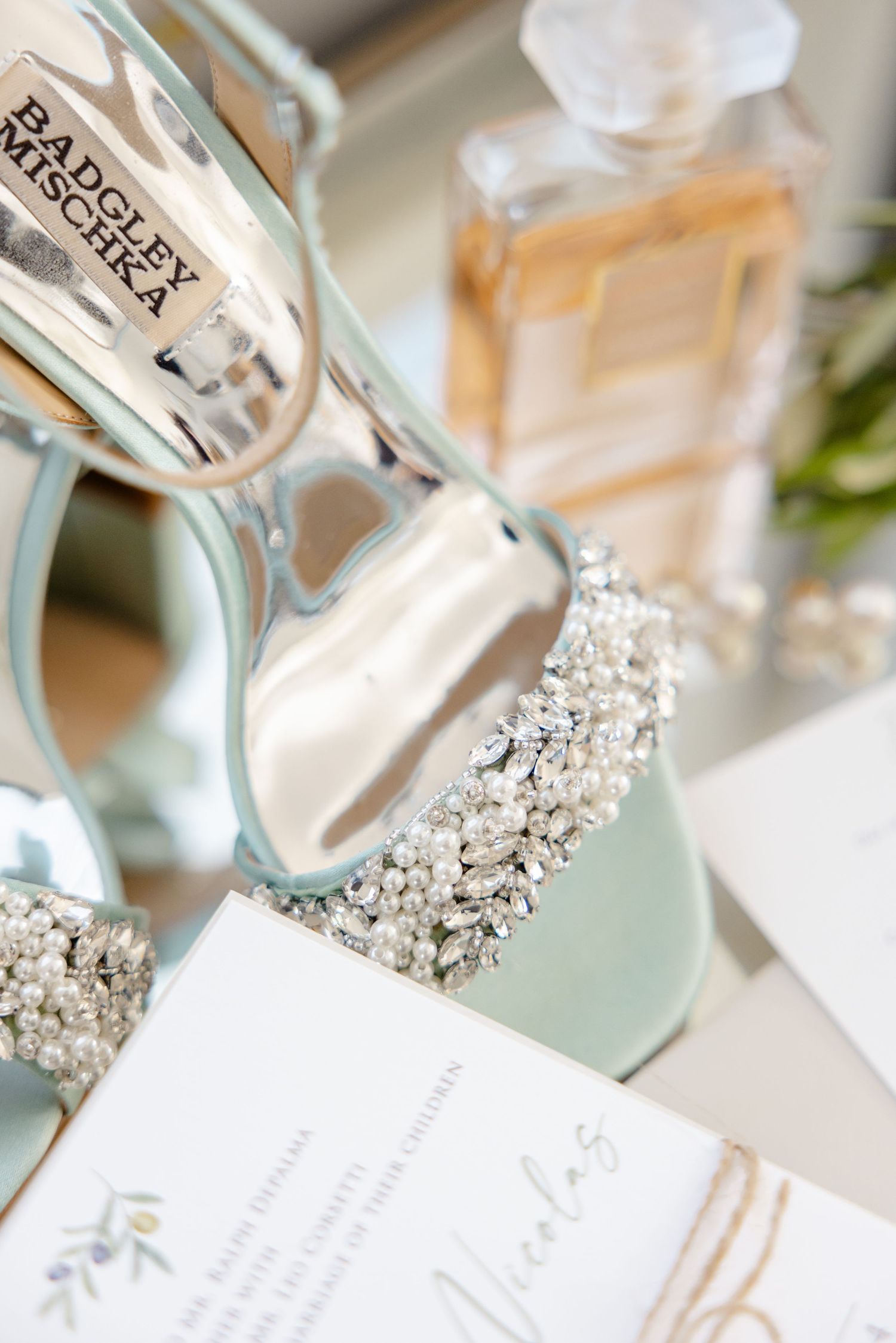Crystal-embellished mint green bridal shoes with perfume bottle and wedding stationery.