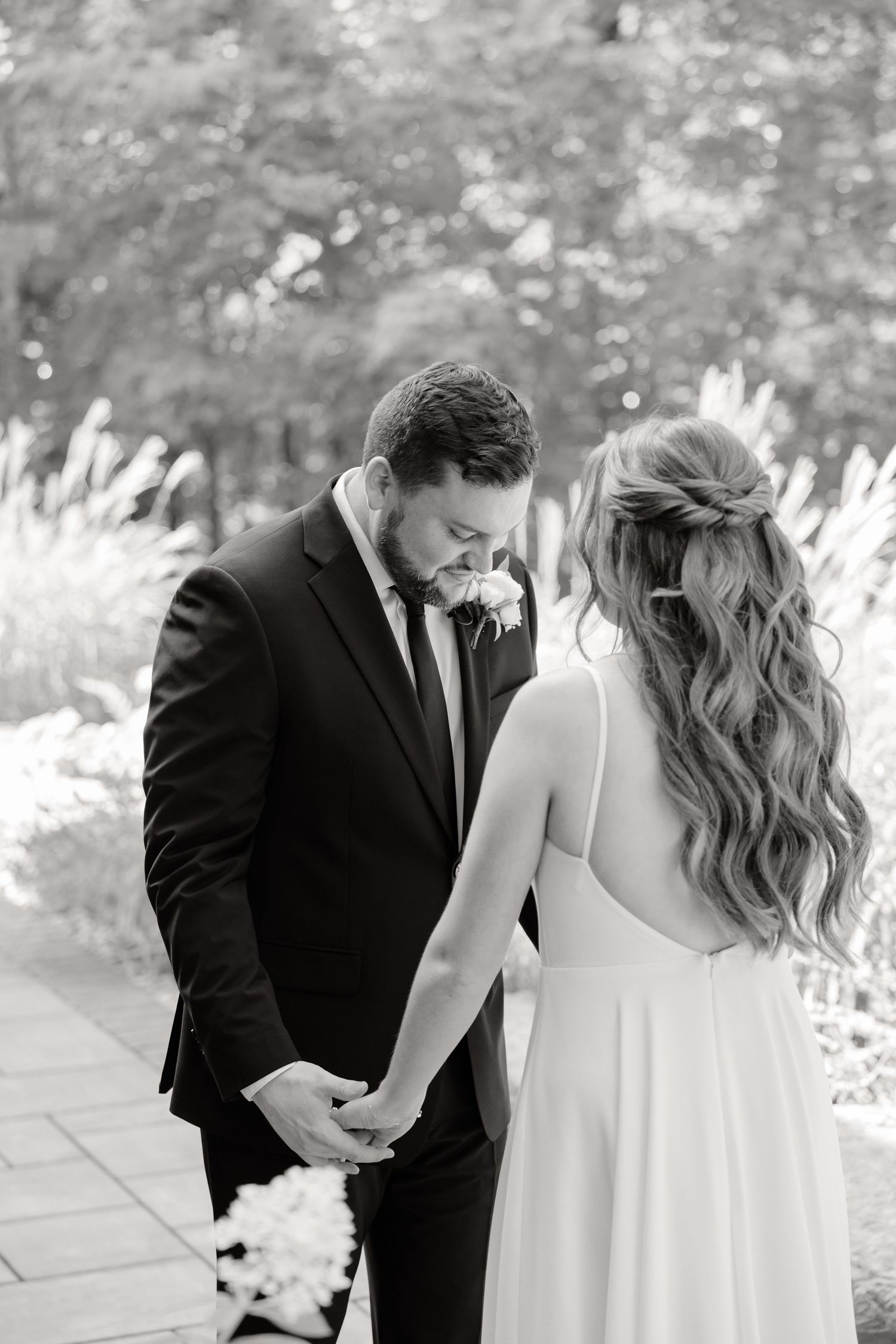 Wedding couple shares an intimate moment on a stone path with ornamental grasses in the background.