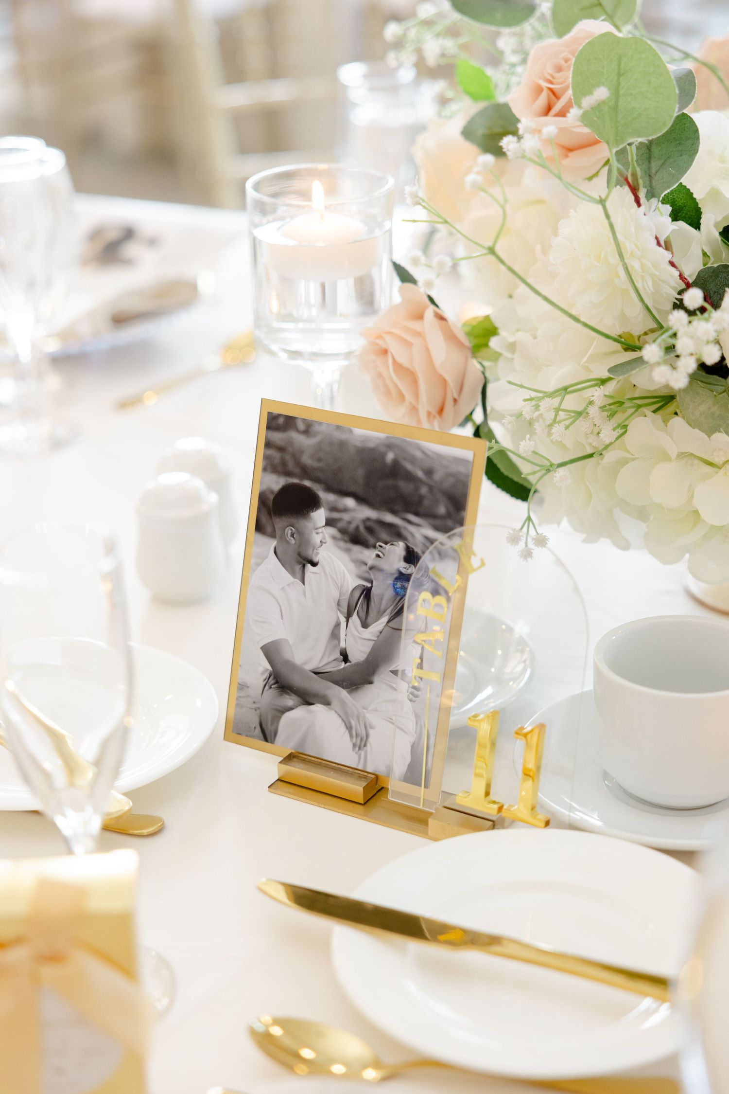 Delicate floral centerpiece with vintage-style photograph display and gold table accents.