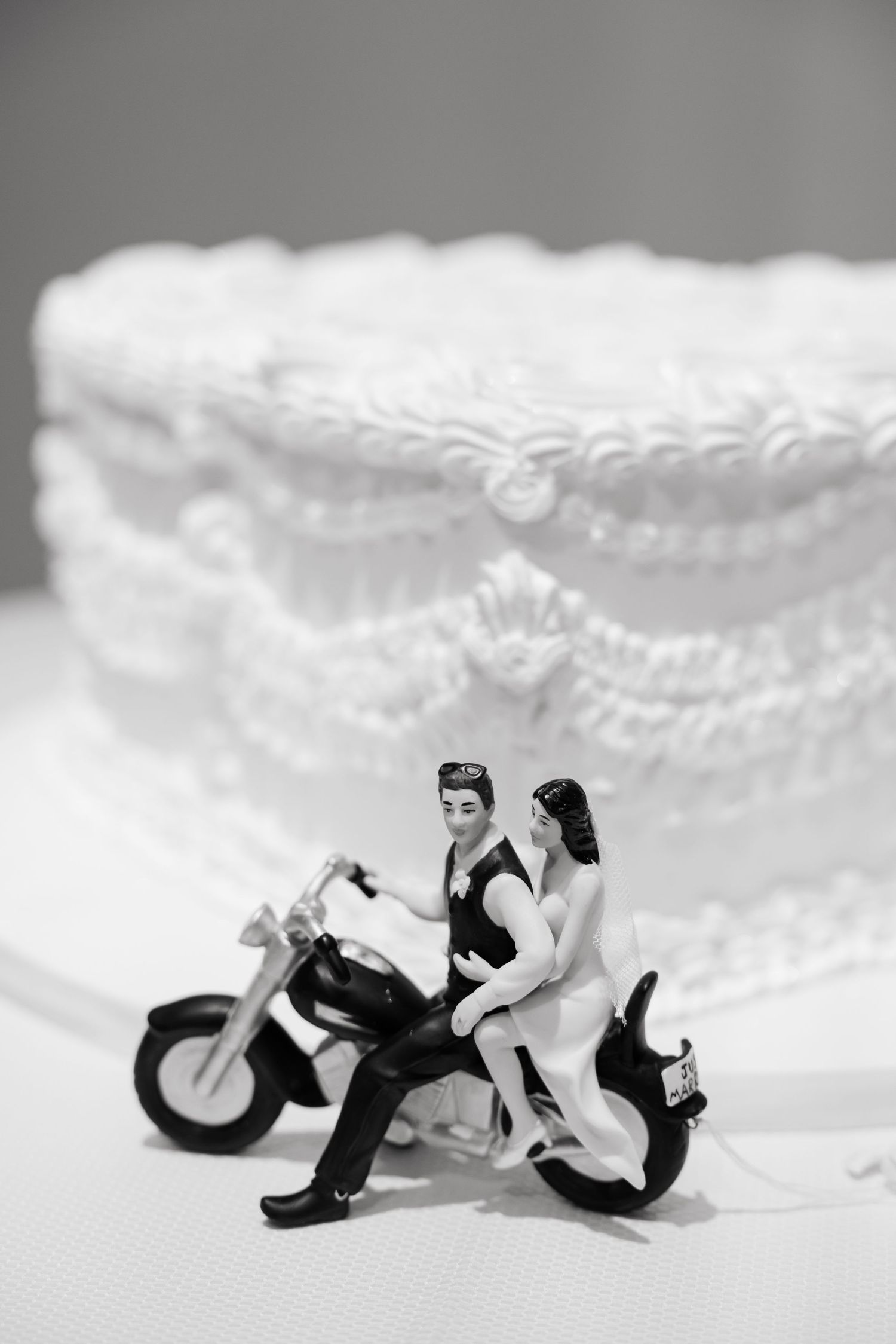 Miniature motorcycle wedding cake topper in black and white against lace background.
